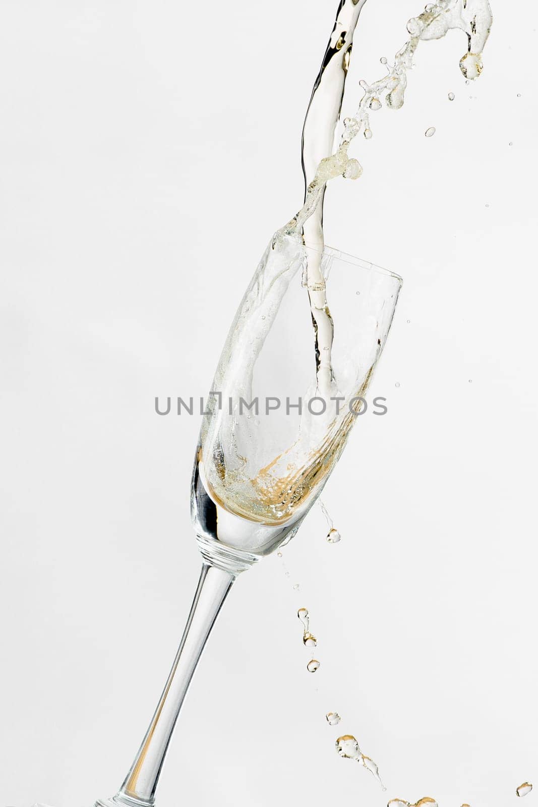 White wine splashing out of glass, isolated on white background