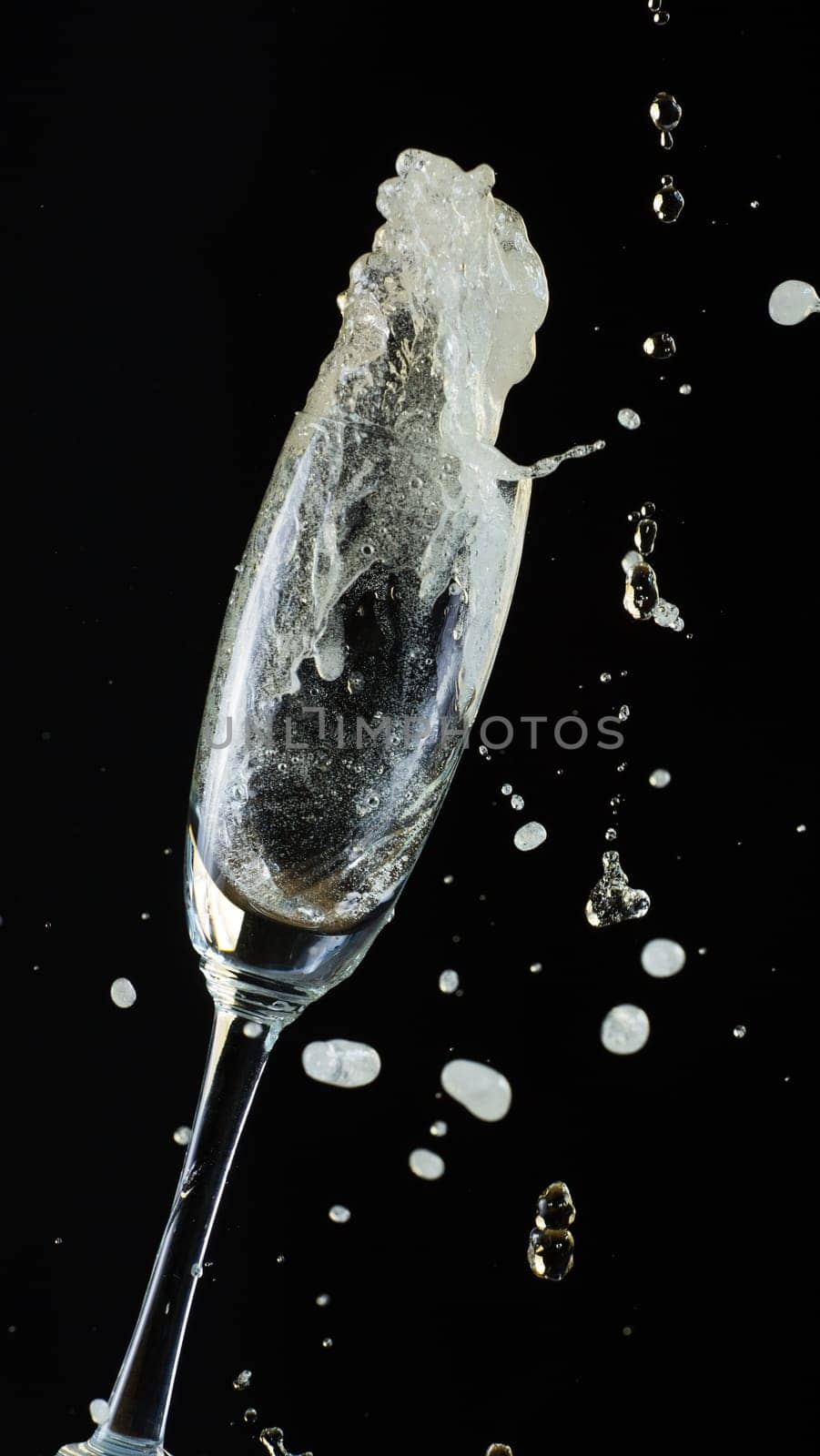Glass of champagne with splash, isolated on black background
