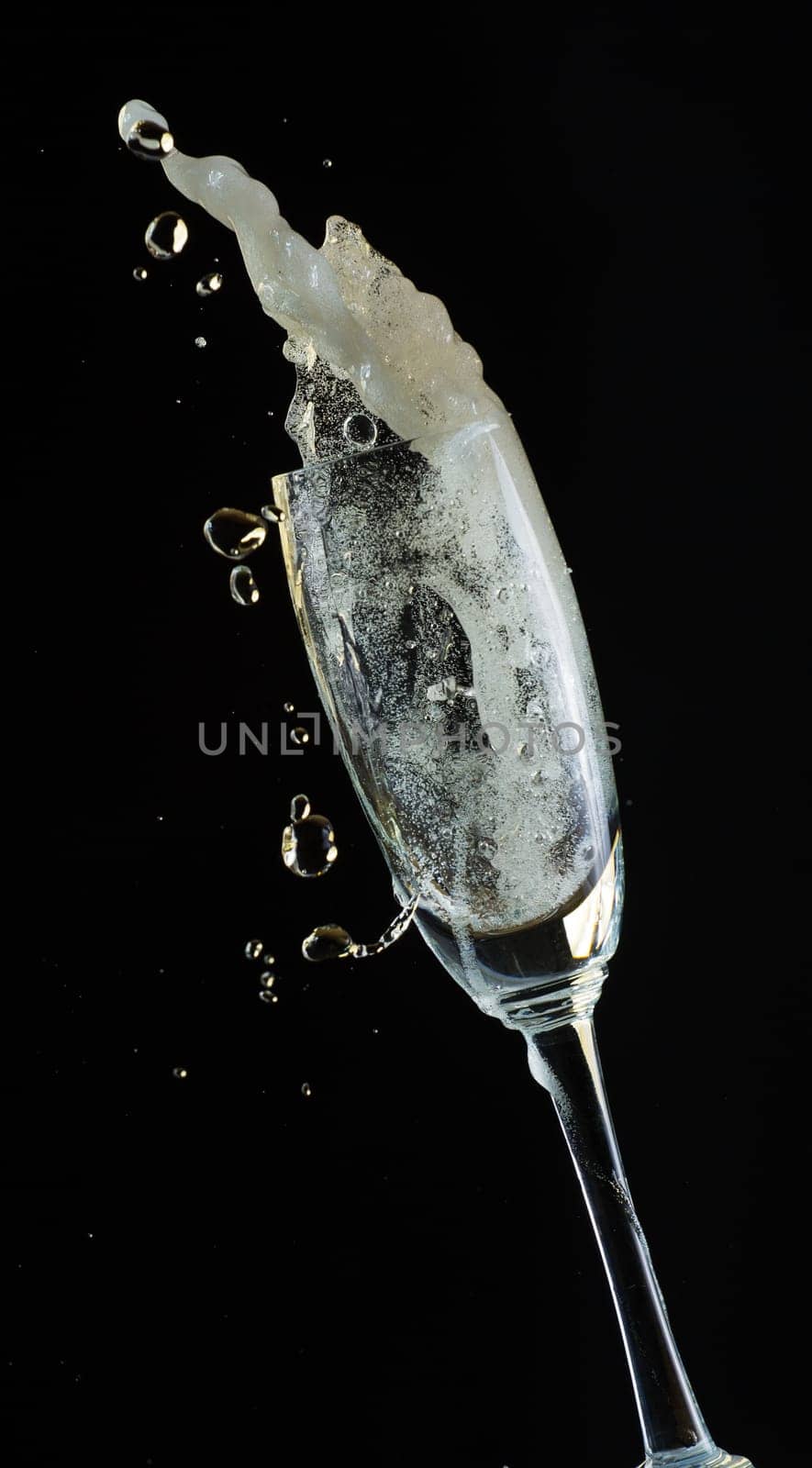 Glass of champagne with splash, isolated on black background