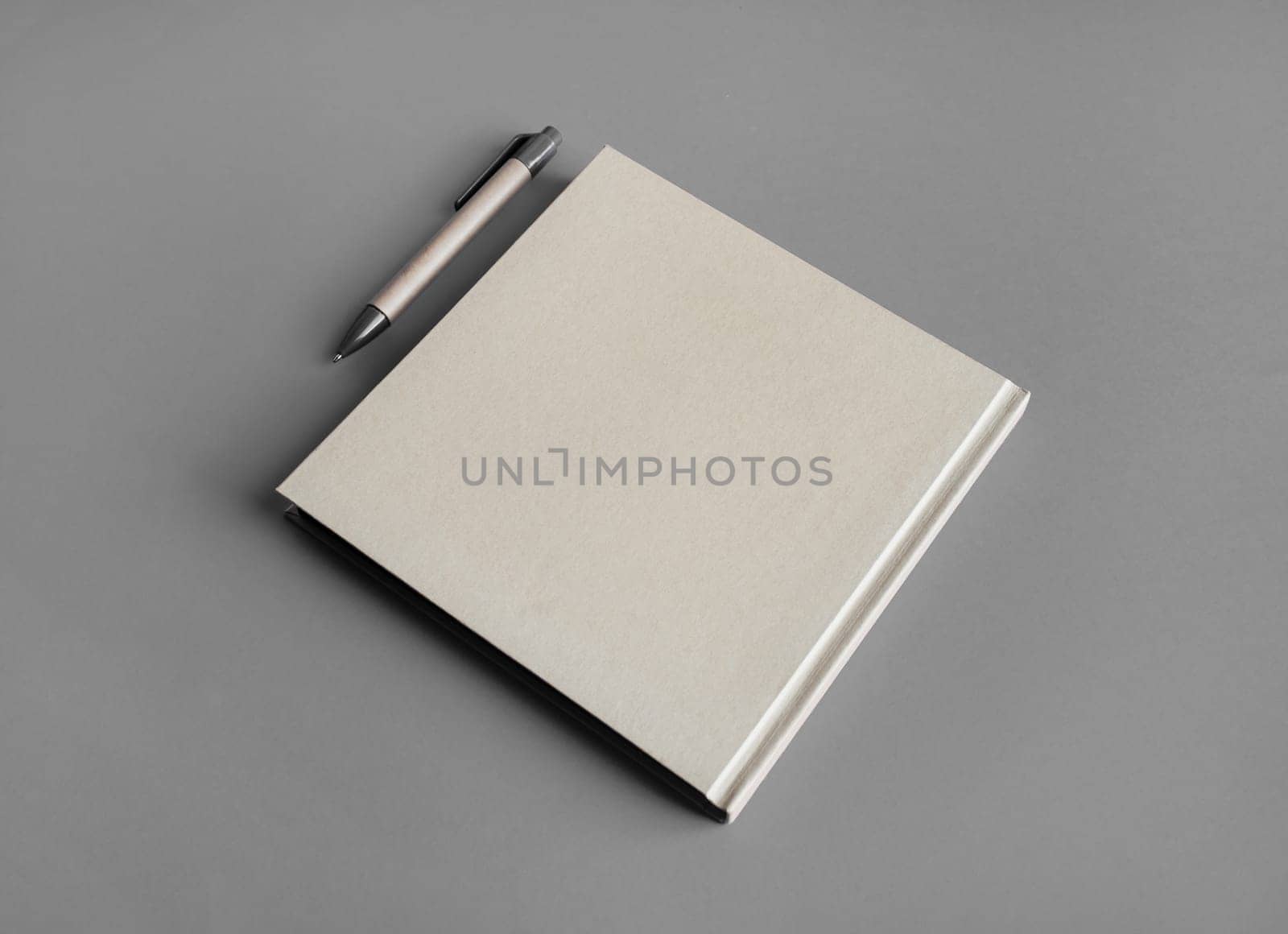 Photo of closed blank kraft brochure and pen on gray paper background. Template for placing your design.