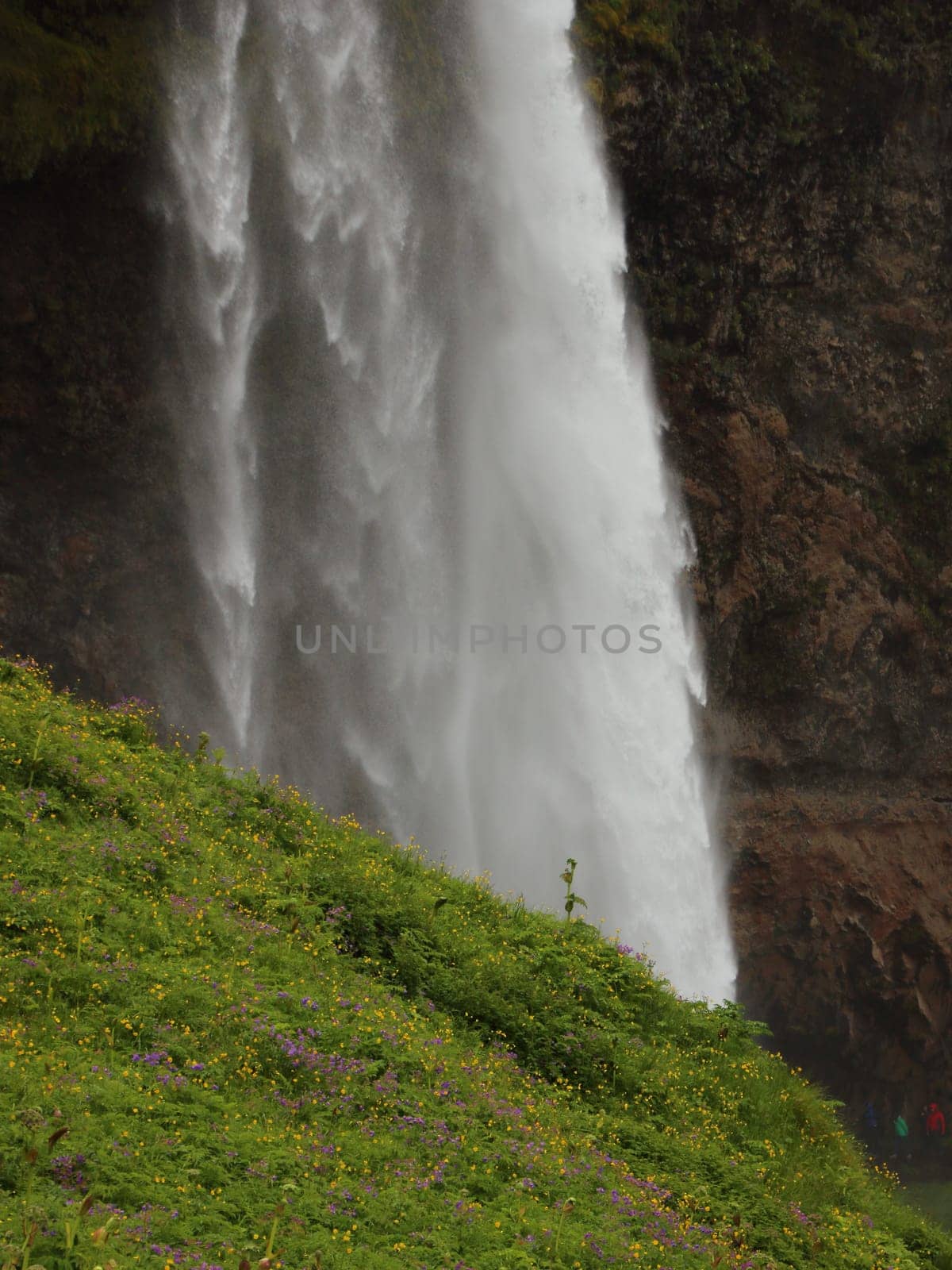 White Waterfall contrast to Green Mountain Hillside with Rocks