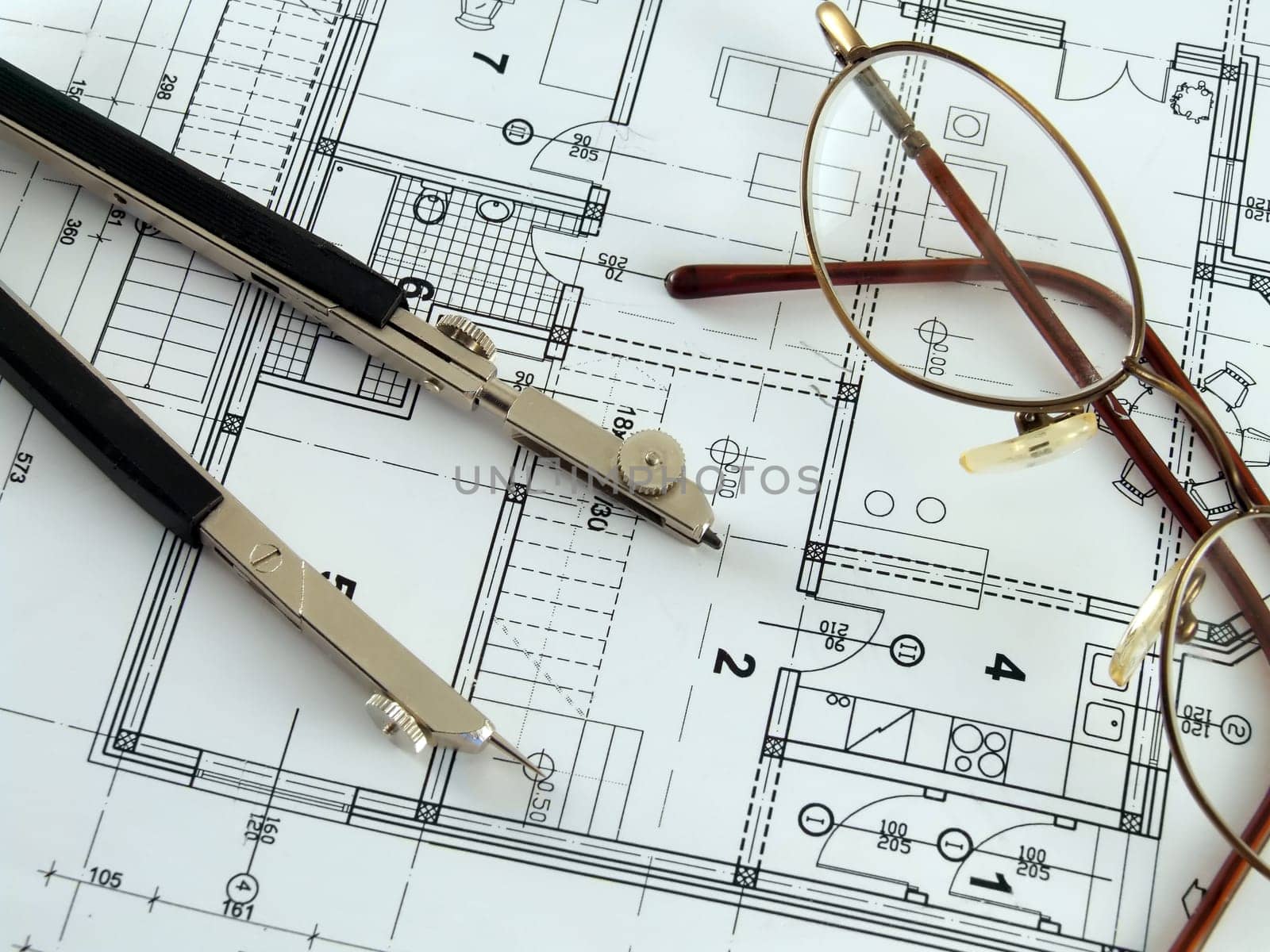 Divider and spectacles laying on architectural plan