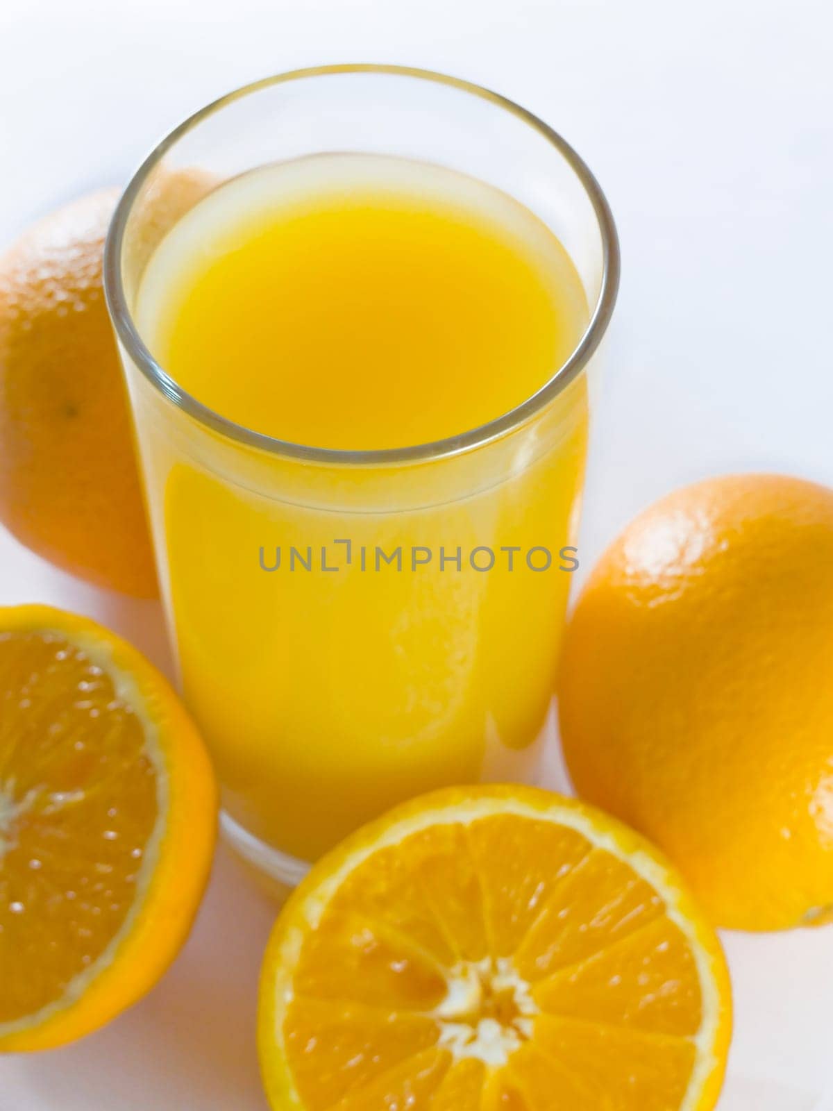 closeup orange juiceand few oranges on white