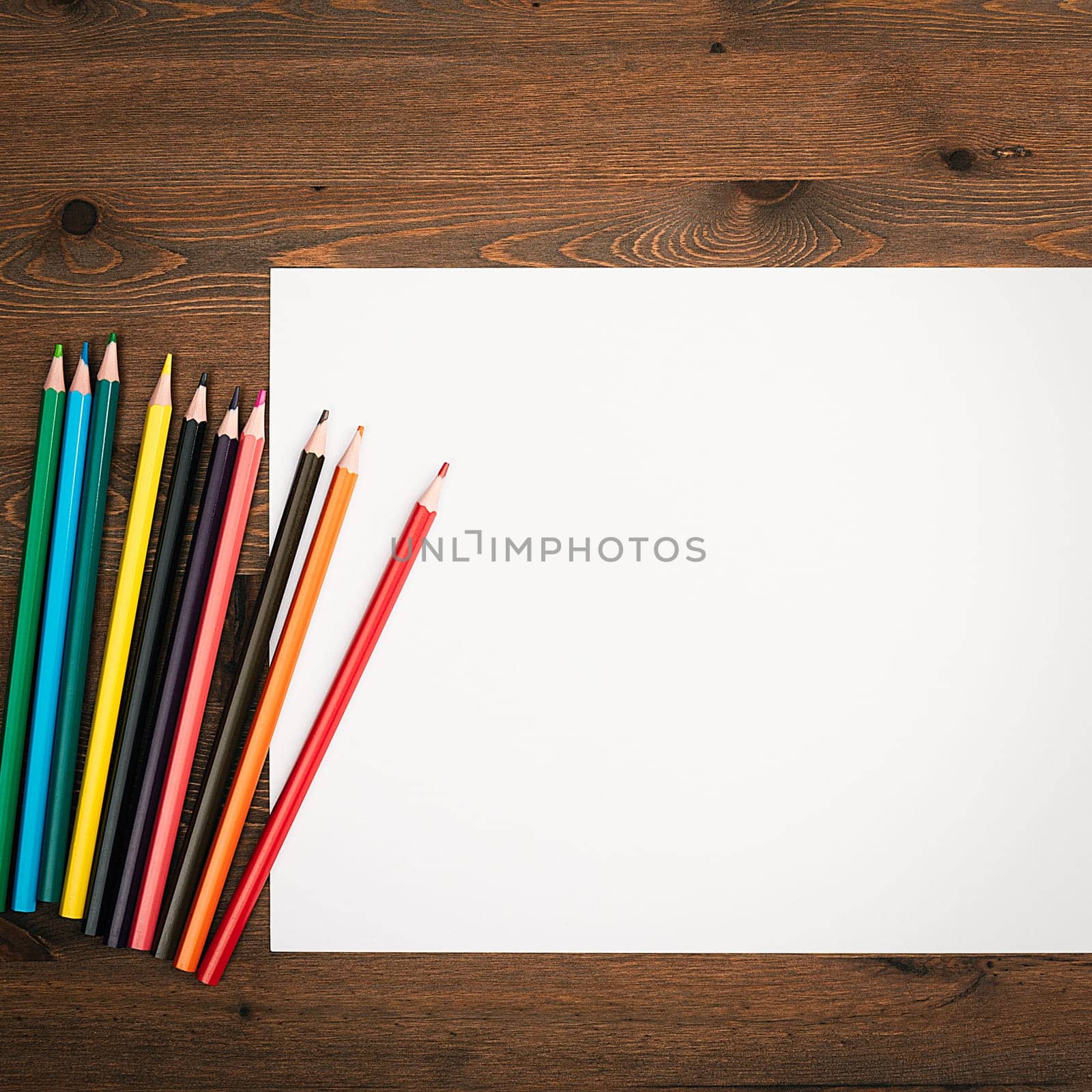 The sheet is pure white and colored pencils for drawing on a wooden background with a place to copy. Mock-up, mockup, layout.