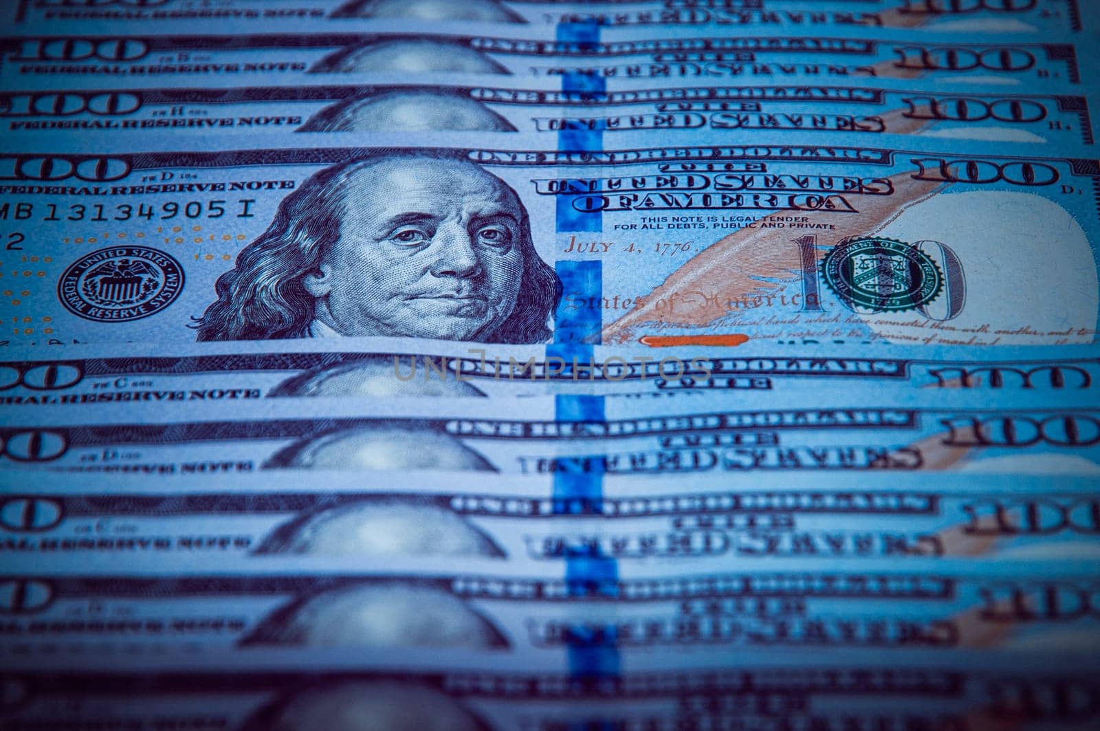 One hundred dollar bills are in a row, one stands out, selective focus. Style blue color.