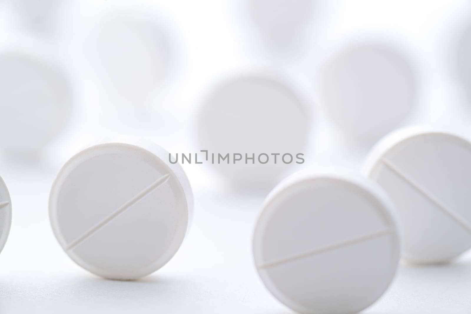 A pile of white pills scattered on a bright white background. Selective focus. Mockup layout, template.