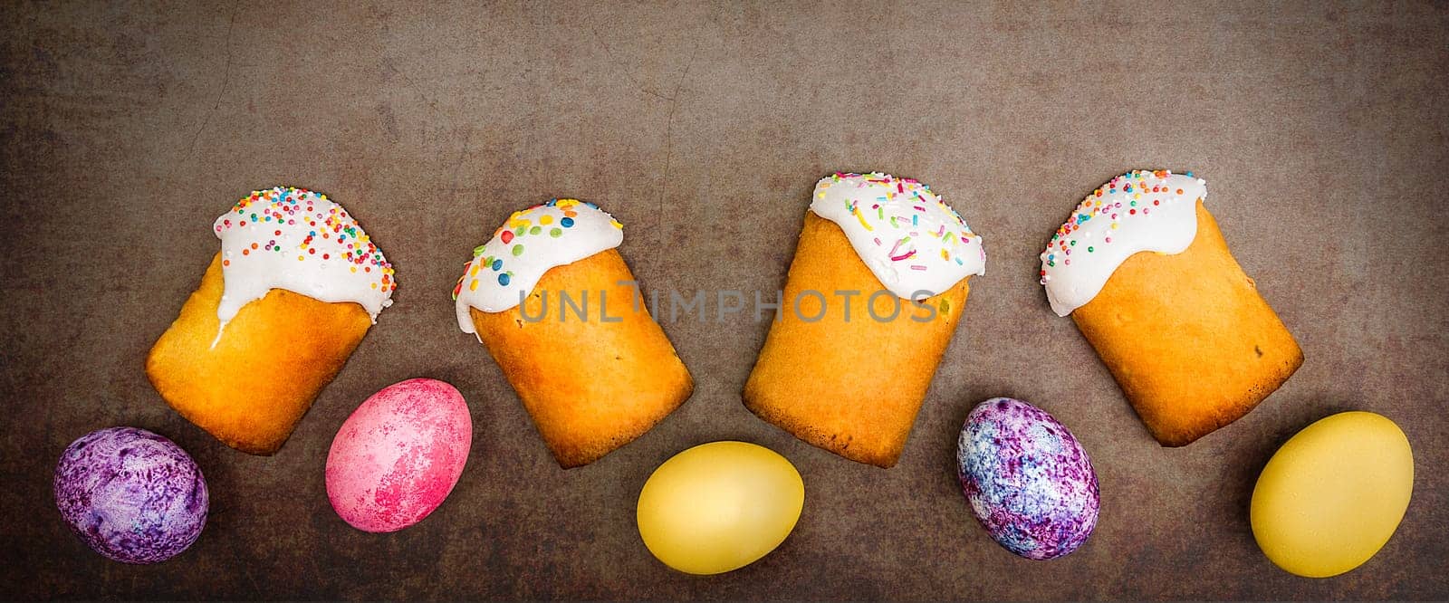 Easter cakes and Easter colored eggs on a dark background. Religious holiday of bright Easter.