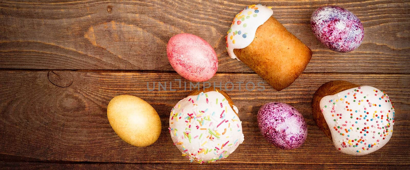Easter cakes and Easter colored eggs on a wooden background. Religious holiday of bright Easter.