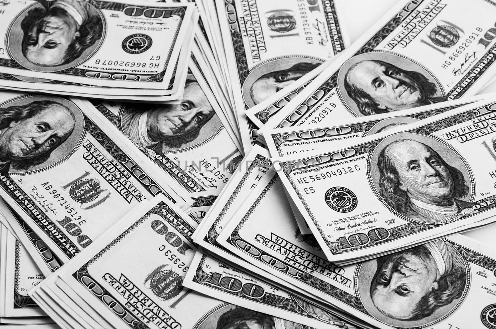 Cash of hundred dollar bills, dollar background image. One hundred US banknotes are scattered over the background. The style is black and white.