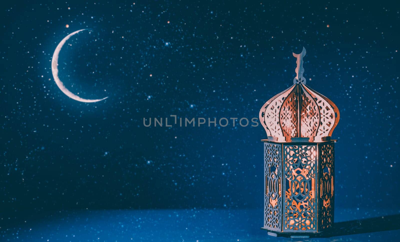 Ornamental Arabic lantern with crescent moon glowing at night. Festive greeting card for Muslim holy month Ramadan Kareem.