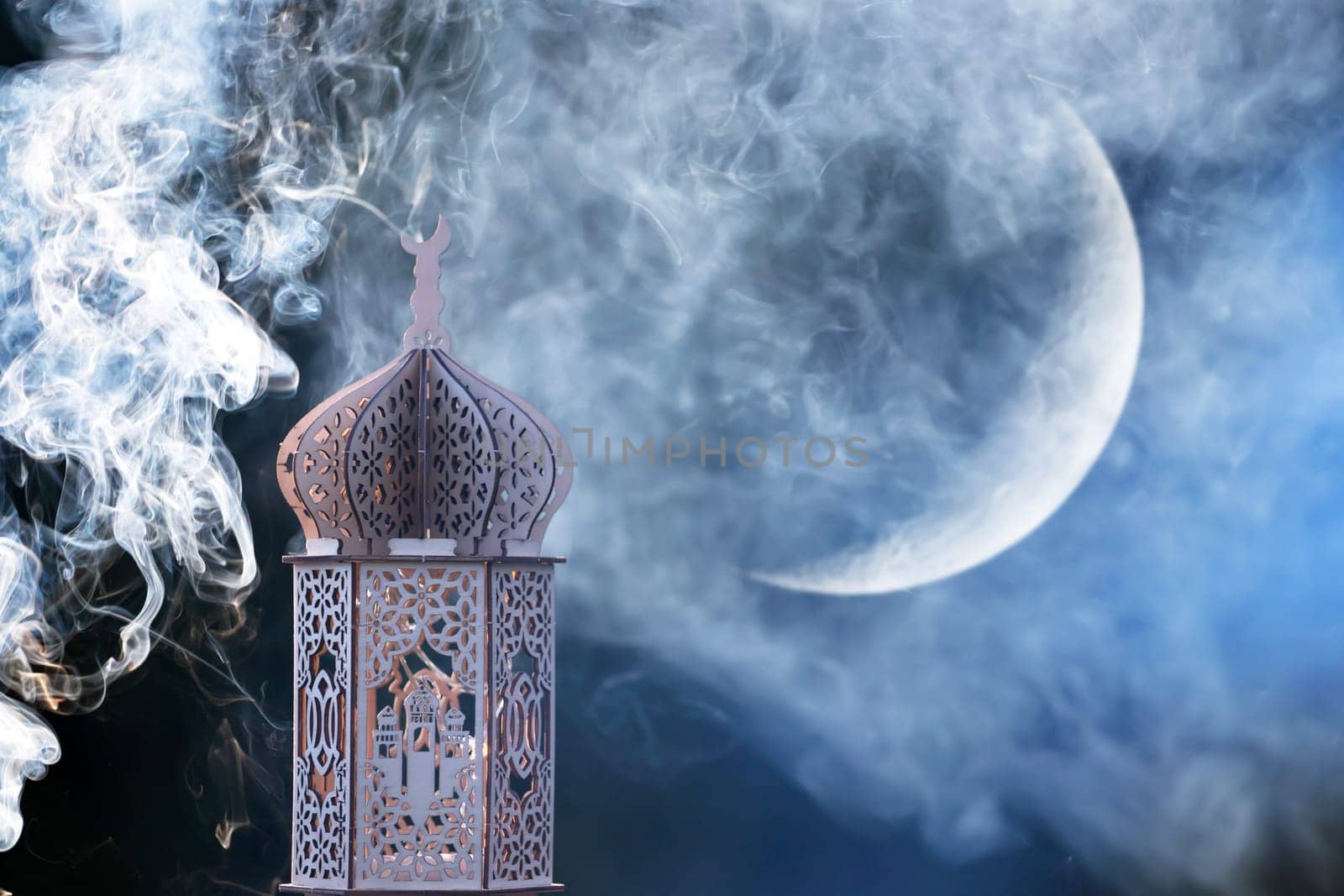 Ornamental Arabic lantern with crescent moon glowing at night. Festive greeting card for Muslim holy month Ramadan Kareem.