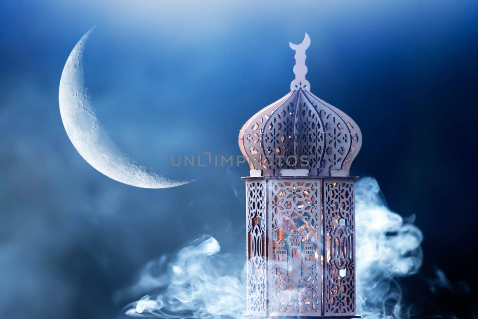 Ornamental Arabic lantern with crescent moon glowing at night. Festive greeting card for Muslim holy month Ramadan Kareem.