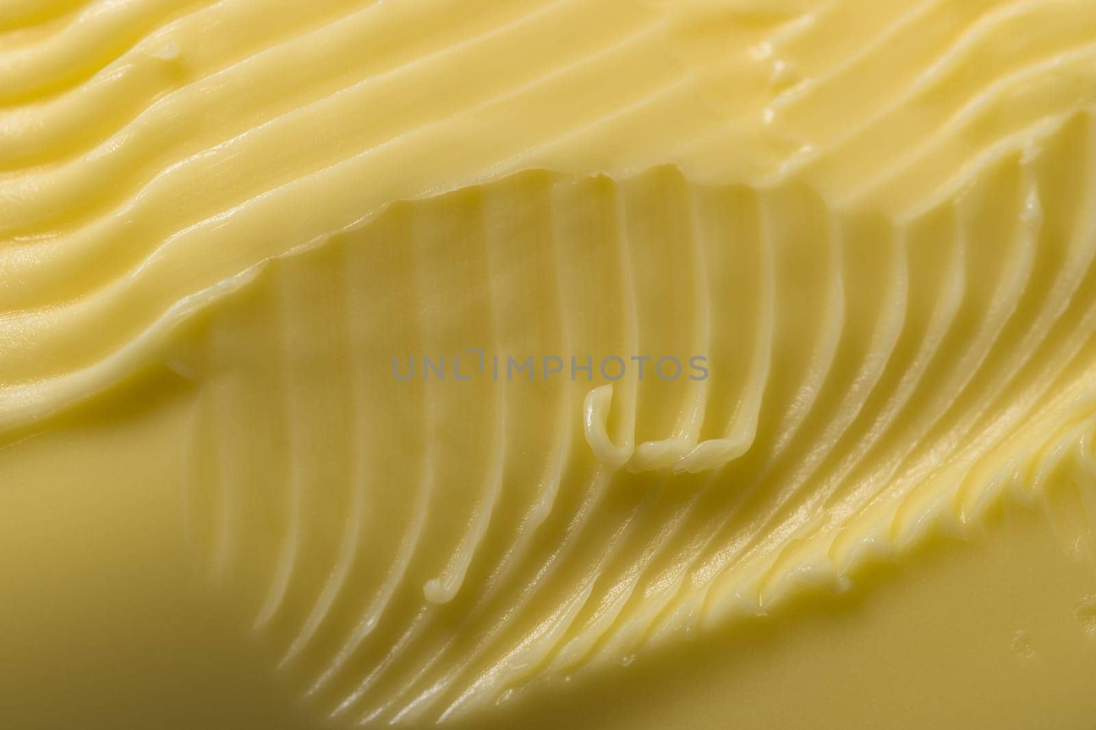 Super close up macro background of intricate grooves and swirls of margarine. Made by a serrated kitchen knife that was swept over the surface.