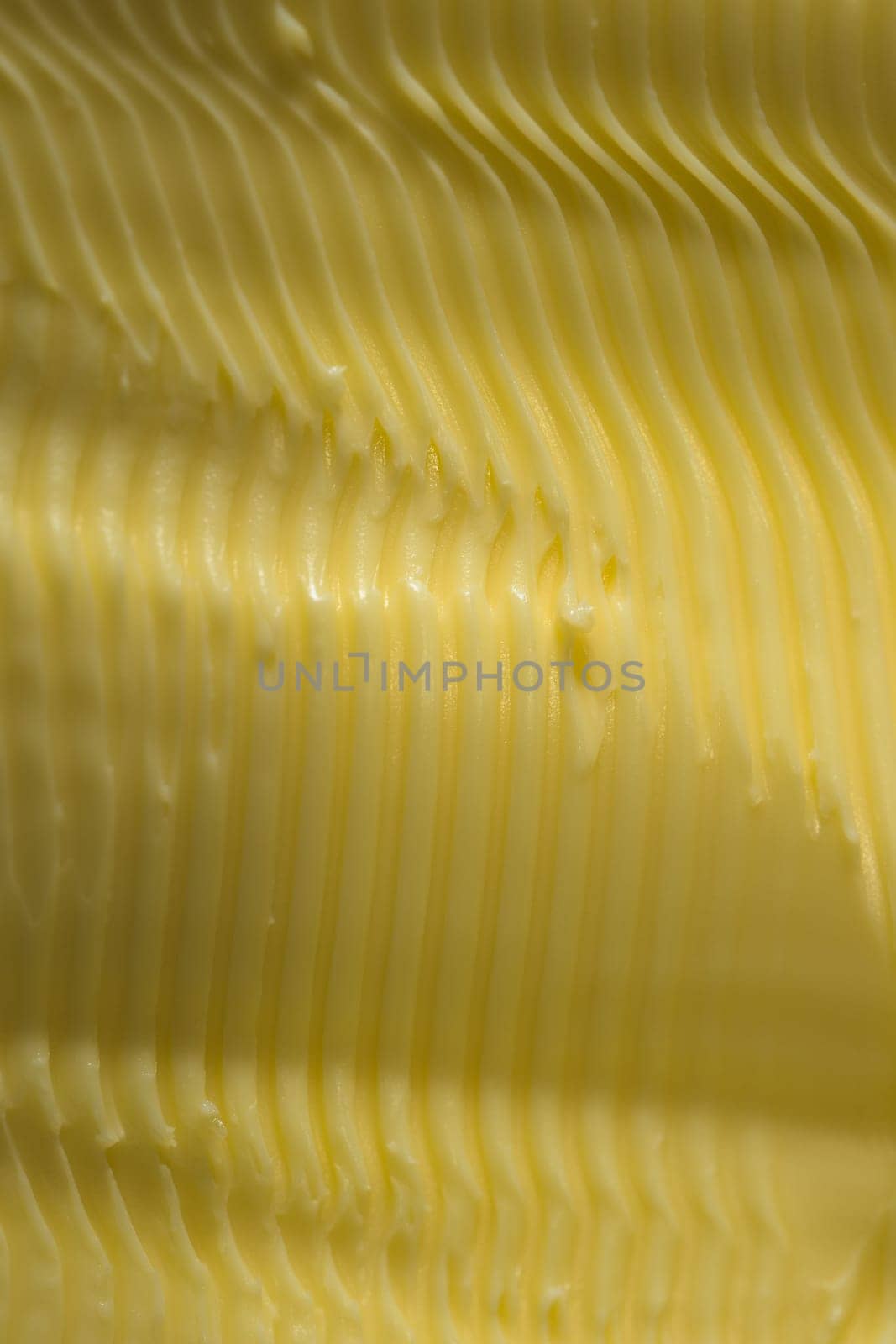 Vertical food texture image. Full frame margarine, textured into wavy ridges using a knife. Commonly found in kitchens as an alternative to butter