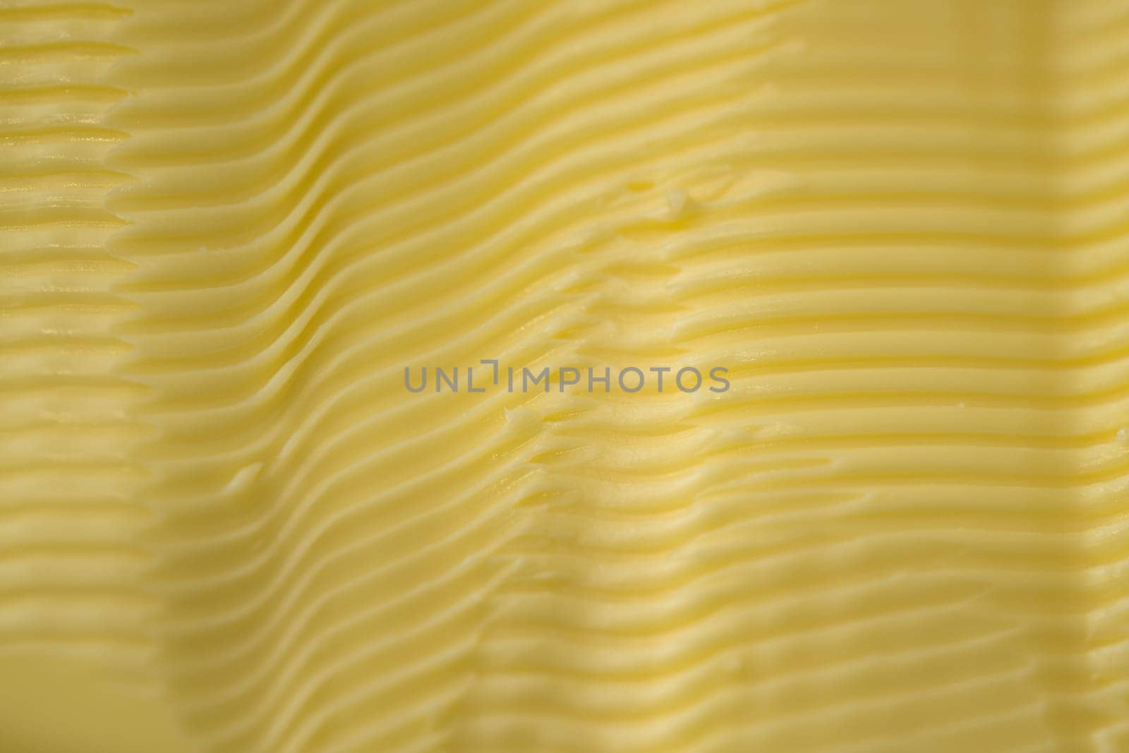 Full frame background texture of ripples in yellow margarine. Possible healthier food choice to traditional butter. Manufactured spreadable diary.