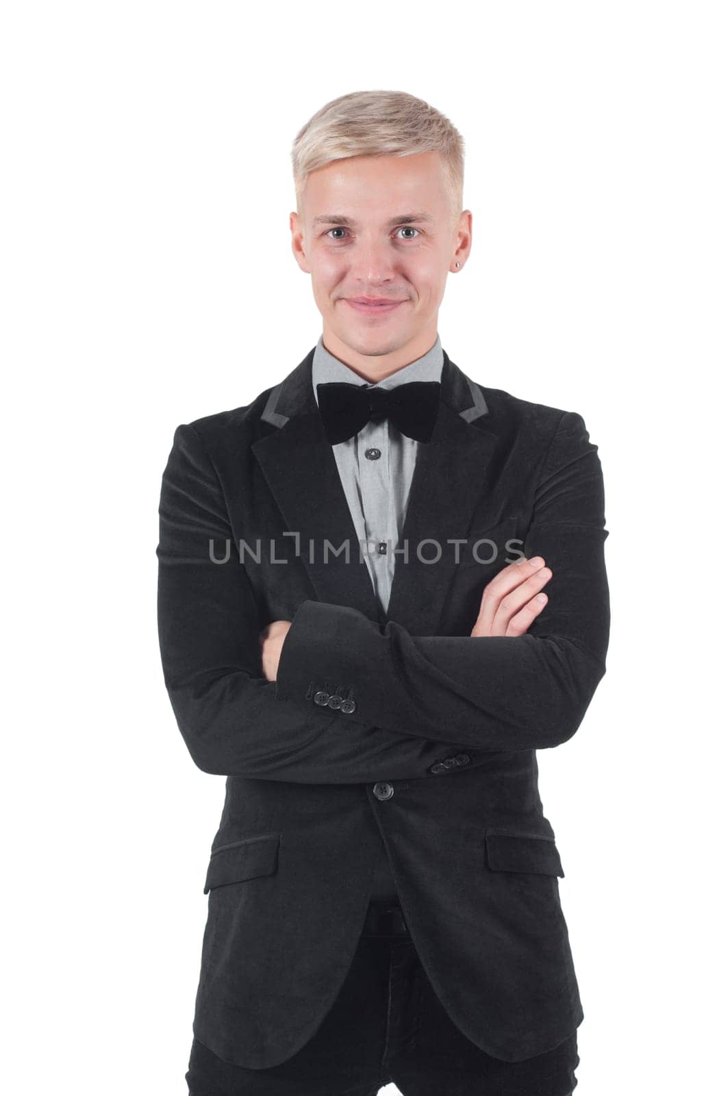 Man in jacket and bow-tie standing with crossed arms.