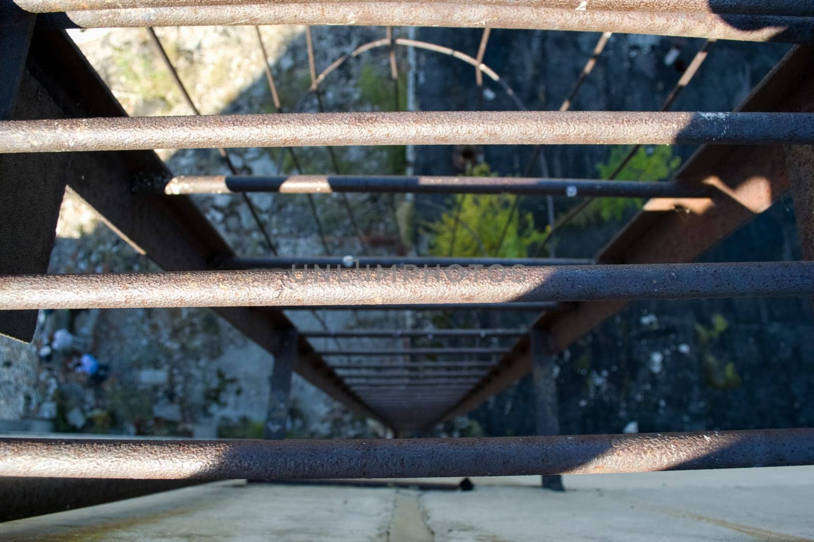 An old rusty staircase to the roof of the building. Abandoned industrial object.