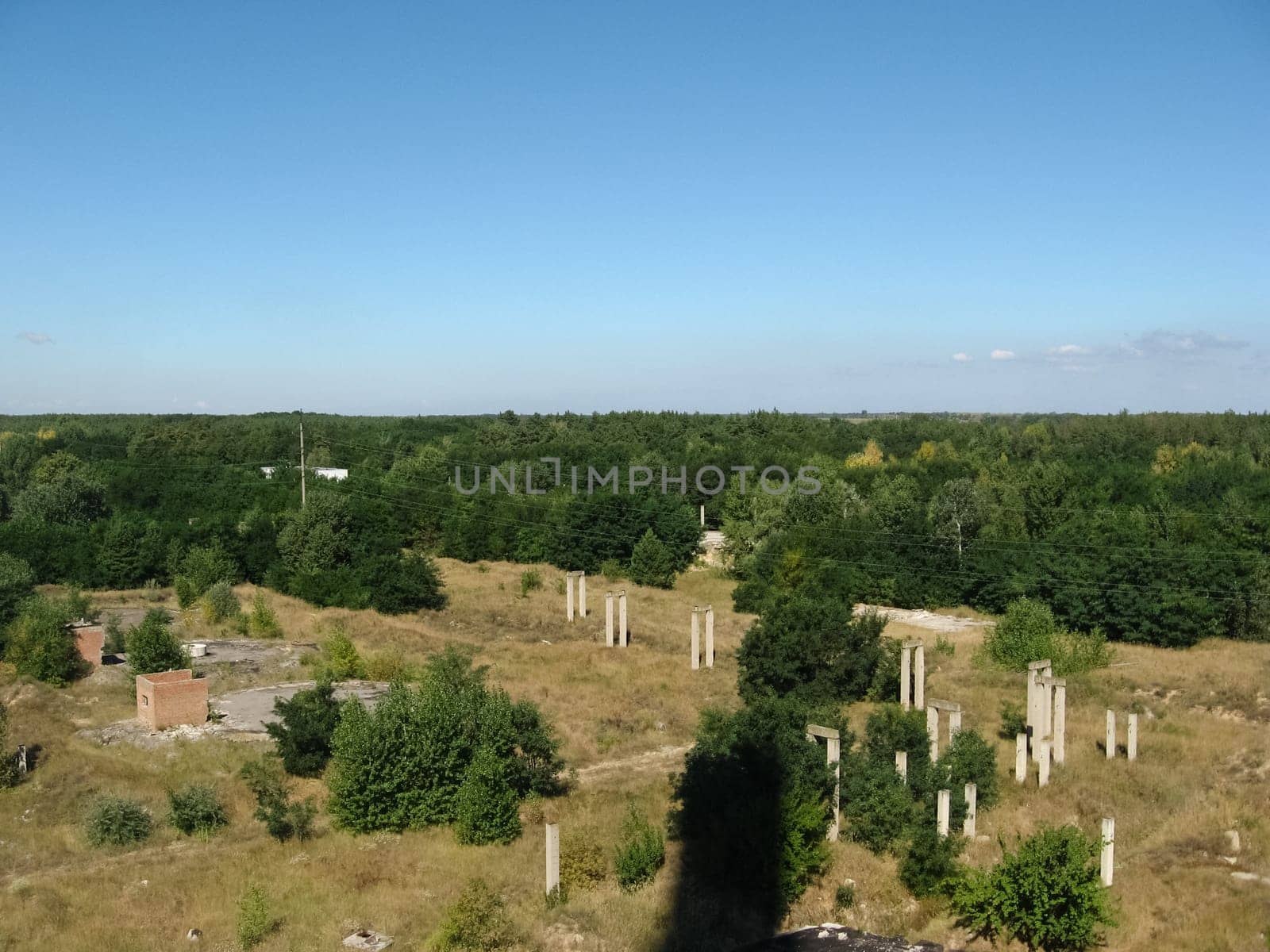 View from above on the site with old destroyed buildings, overgrown grass and trees.