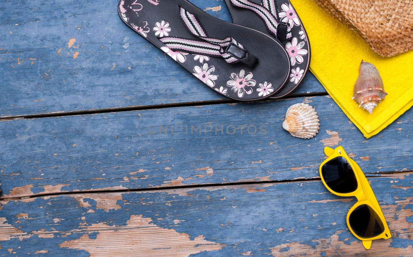 Summer background: Concept of leisure travel in the summer: Straw hat, sunglasses, shells and flip flops. Text space.