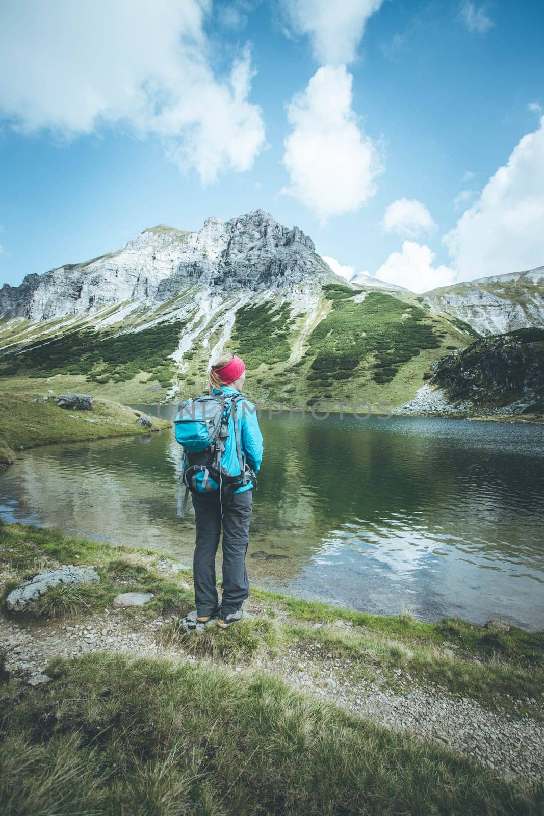 Female blonde mountain climber with backpack is enjoying the view