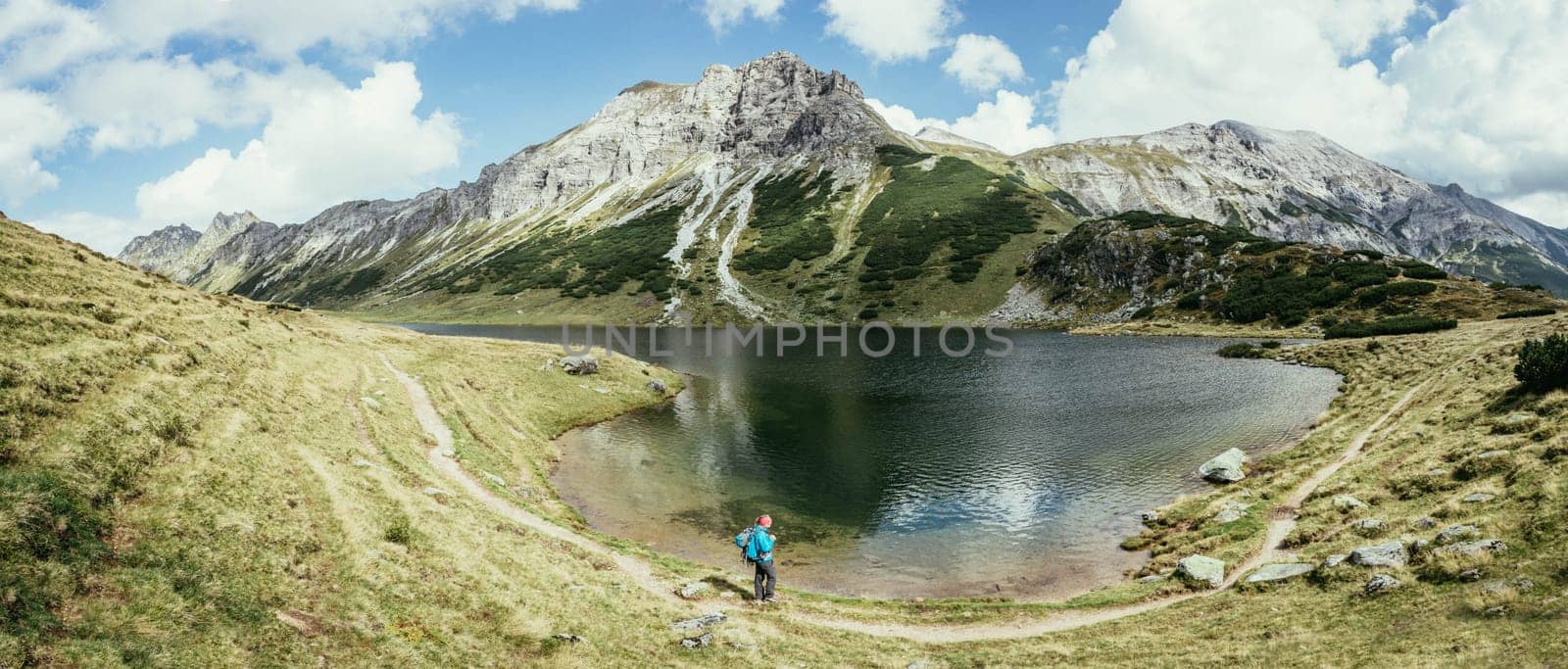Mountain landscape: Rocky mountain range, clear water lake and blue cloudy sky  Panorama