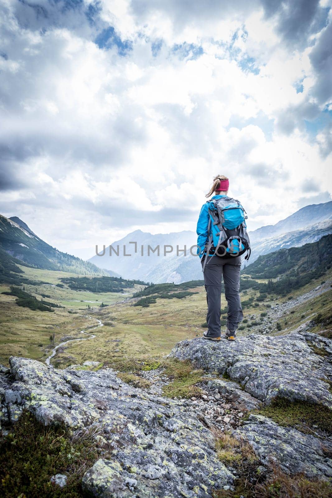 Woman in sportswear and with backpack enjoys the view in the mountains