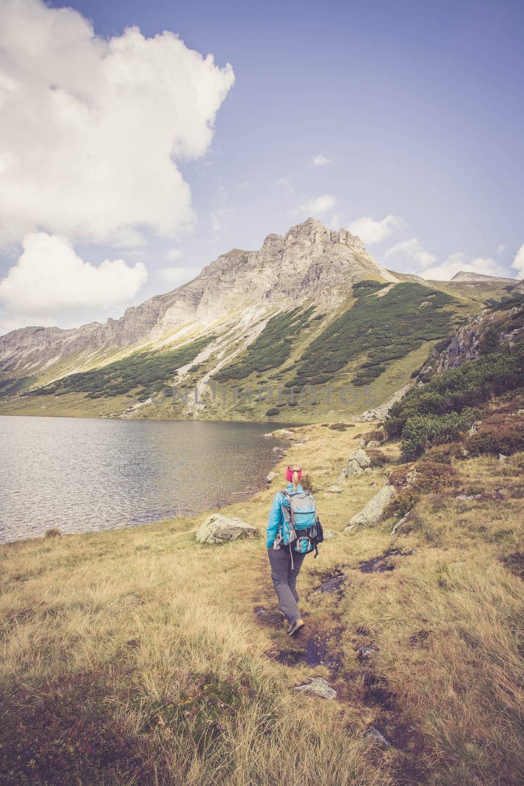Mountain landscape: Rocky mountain range, clear water lake and blue cloudy sky