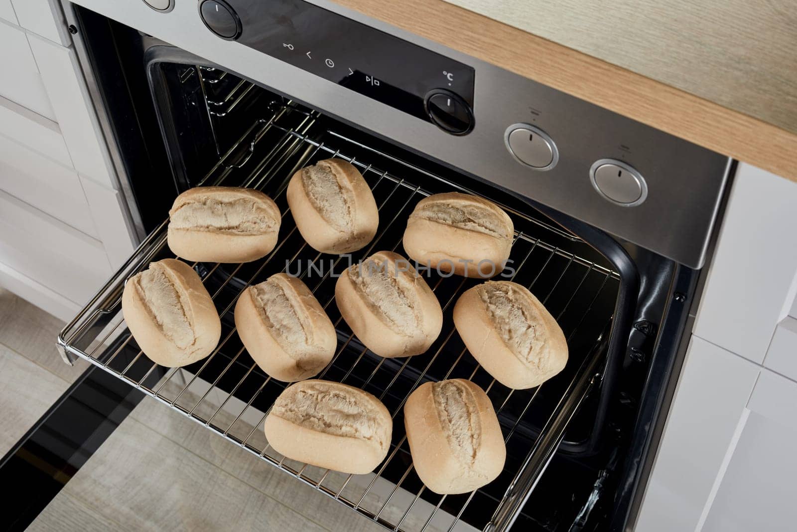 From above raw half baked bread buns on metal rack glide rack in oven