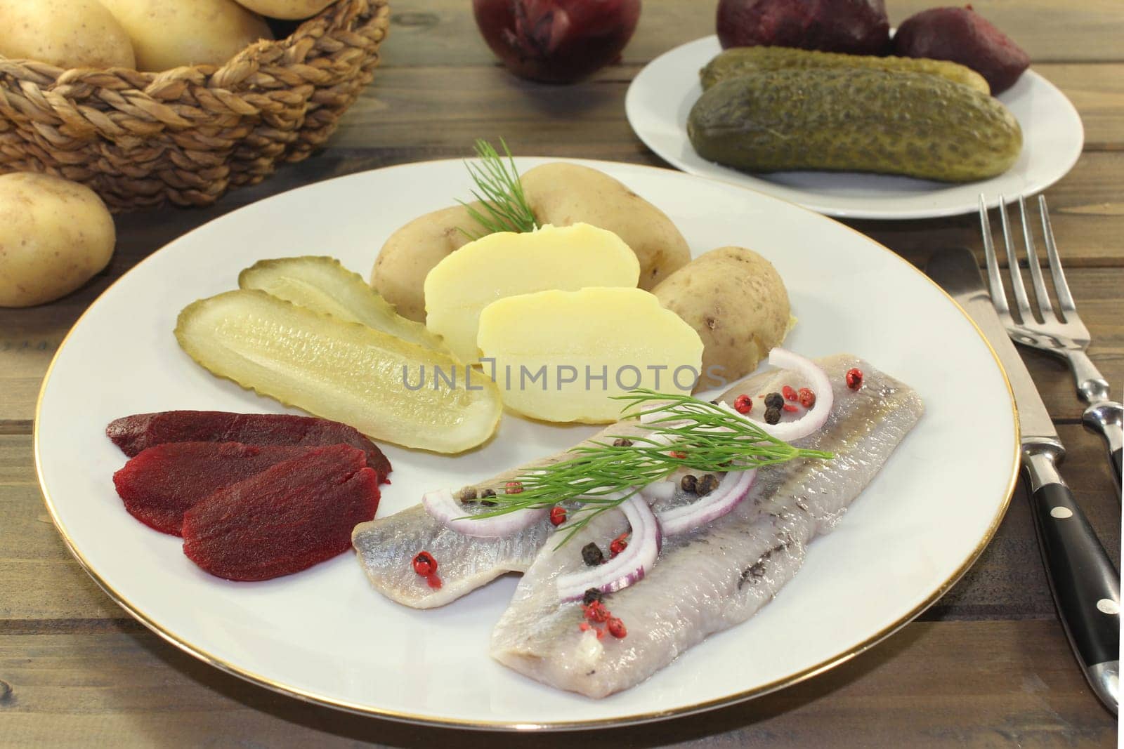 a plate of matjes fillet,peel potatoes,beetroot and sour cucumbers