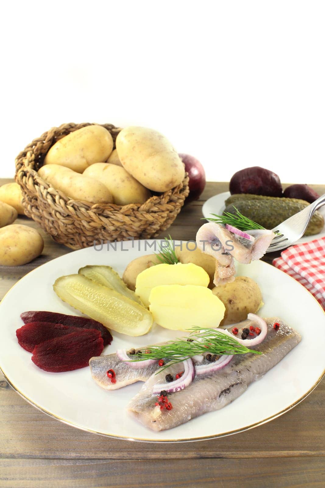 a plate of matjes fillet,peel potatoes,beetroot and sour cucumbers
