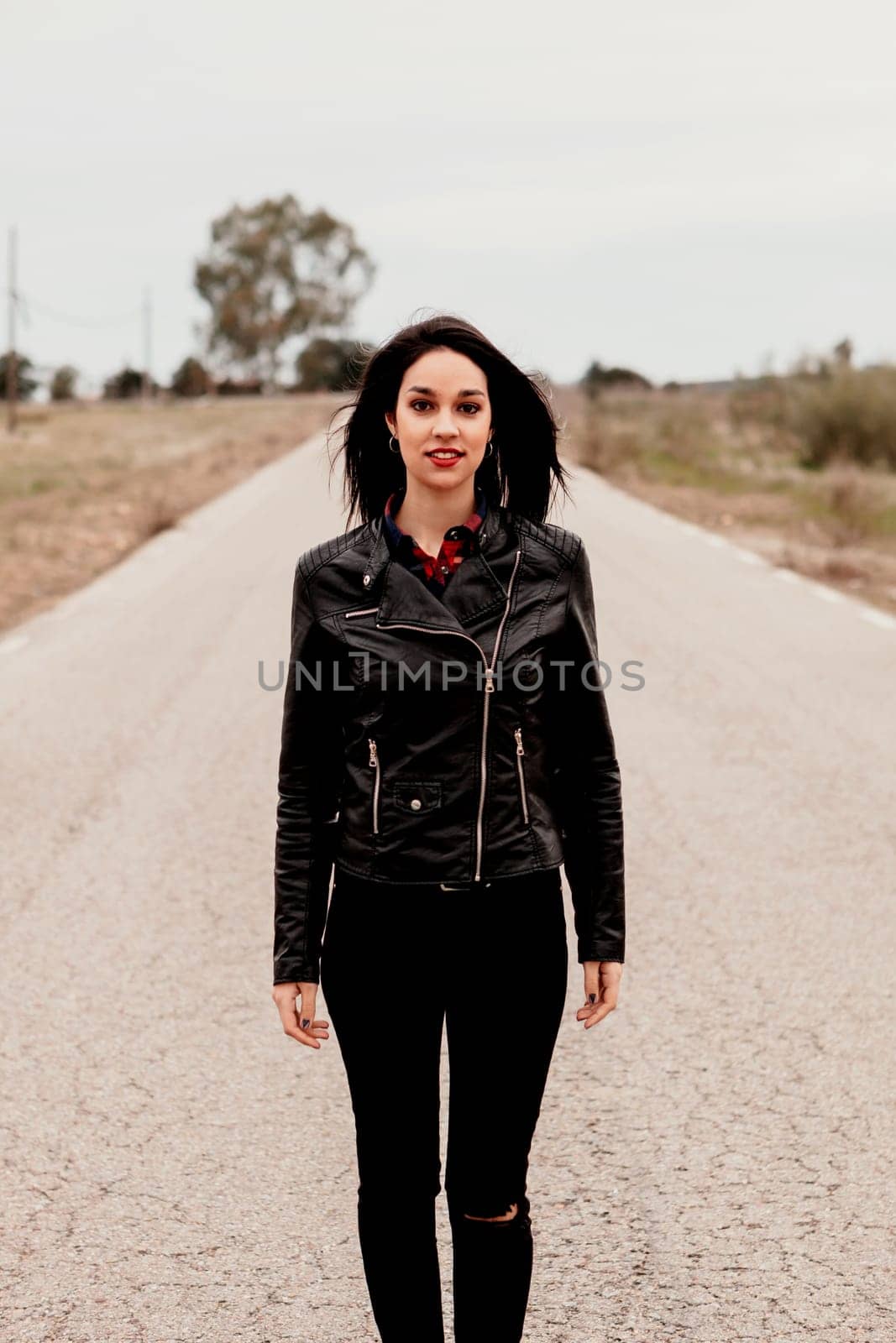 Brunette woman with black leather jacket in a lonely road