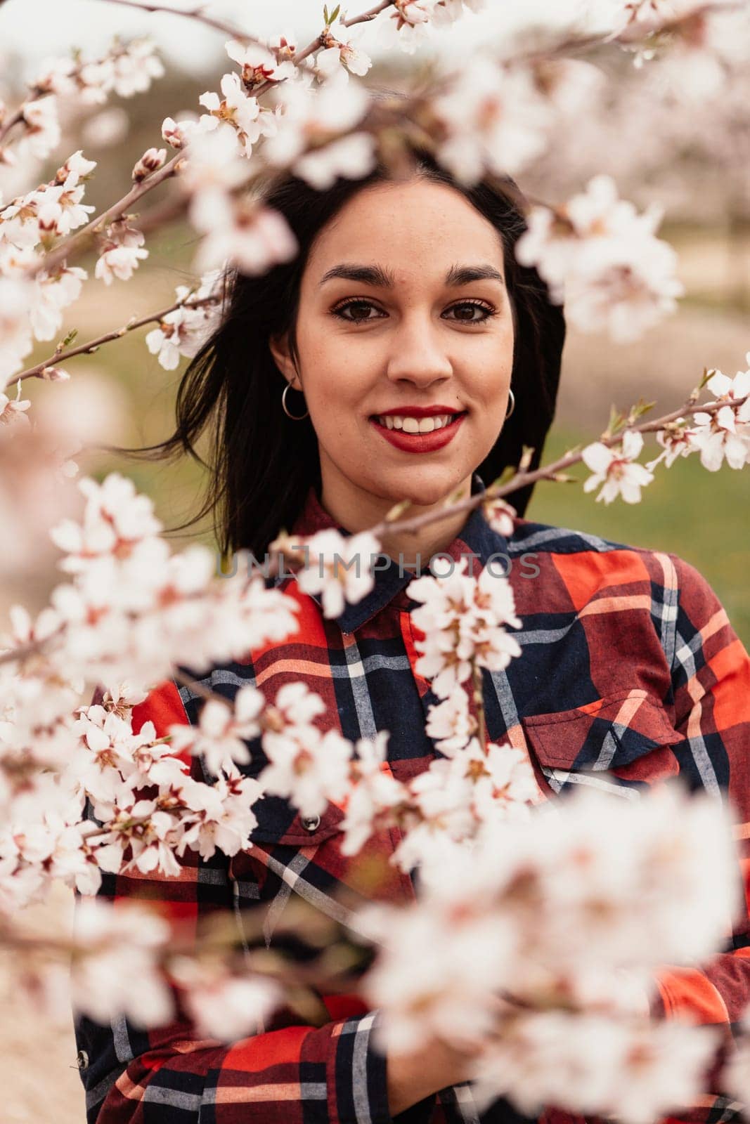 Brunette girl near a almond tree with many flowers