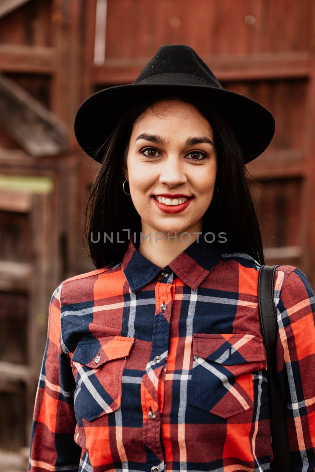 Pretty brunette girl with red plaid shirt and black hat