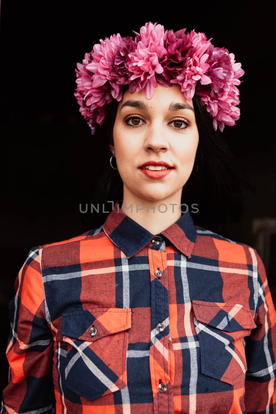 Pretty girl with pink flower crown in her head and a black background