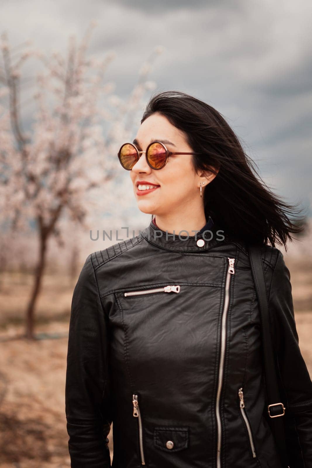 Brunette woman with leather jacket surrounded of flowery trees