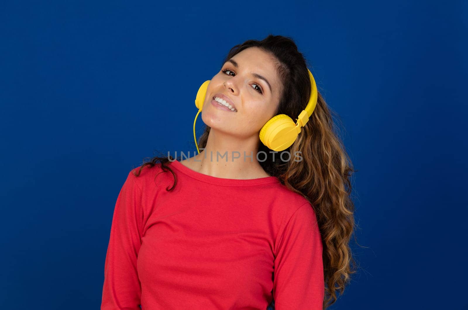 Portrait of beautiful caucasian girl with curly hair and headphones listening music isolated on a white background