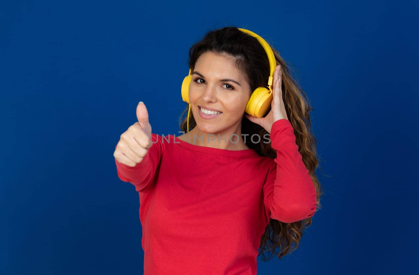Portrait of beautiful caucasian girl with curly hair and headphones listening music isolated on a white background