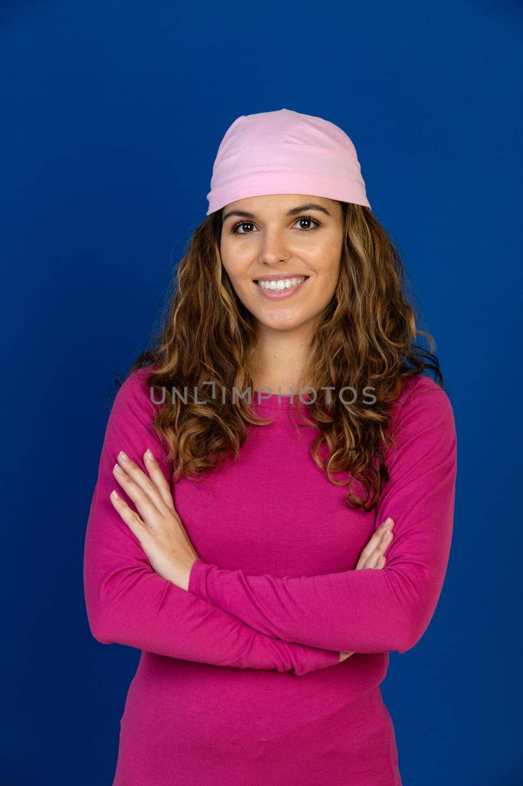 Hopeful woman wearing a pink scarf isolated on a blue background