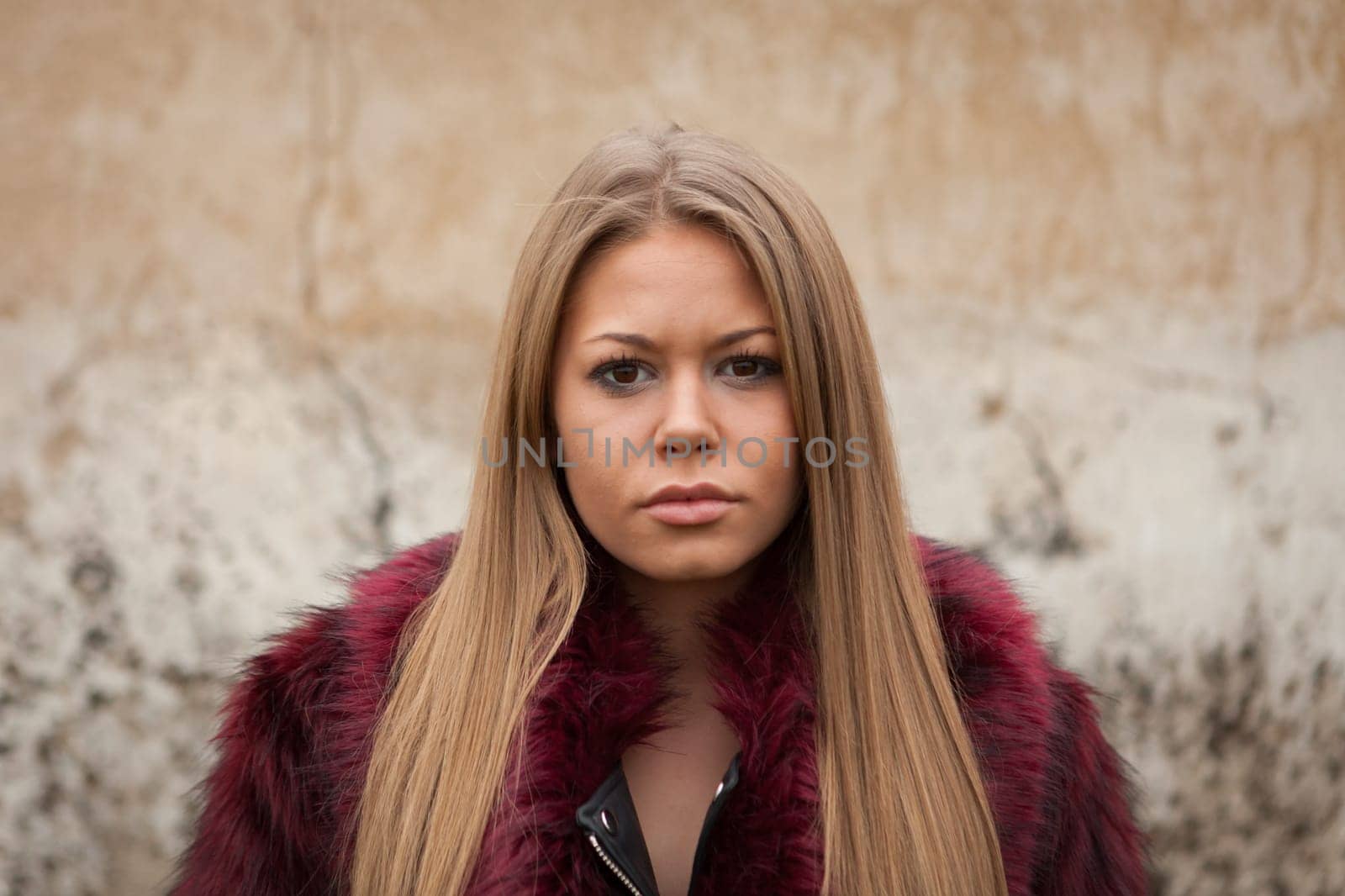 Melancholy young girl with red fur coat looking at camera
