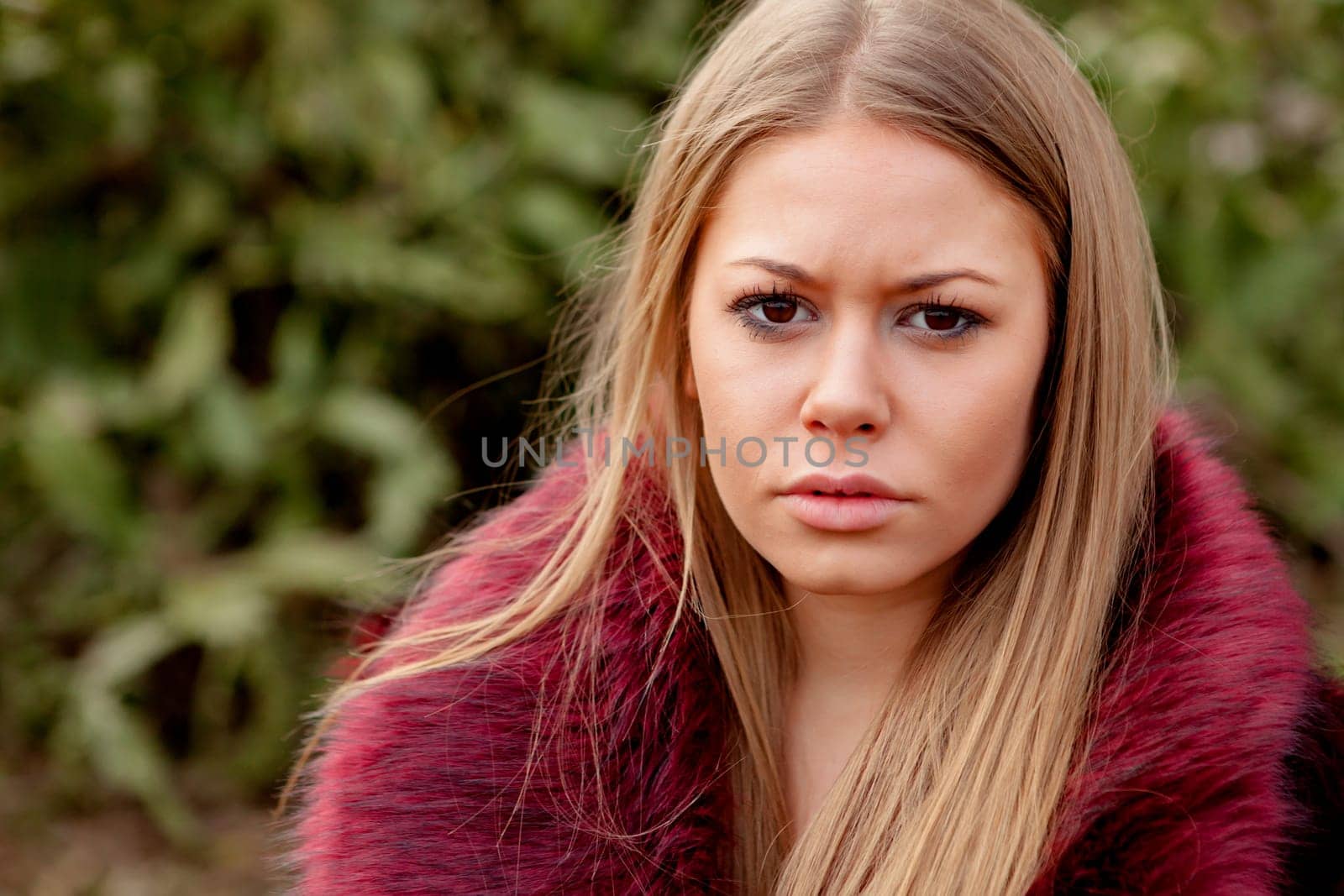 Pretty blonde girl with fur coat in the park at winter