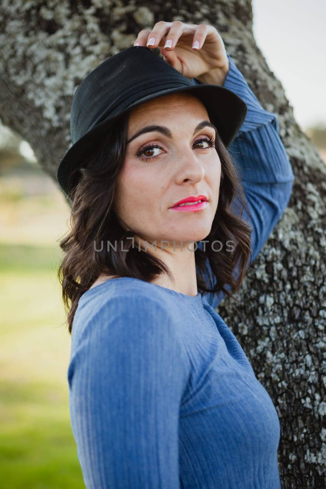 Stylish young woman with black hat in the field