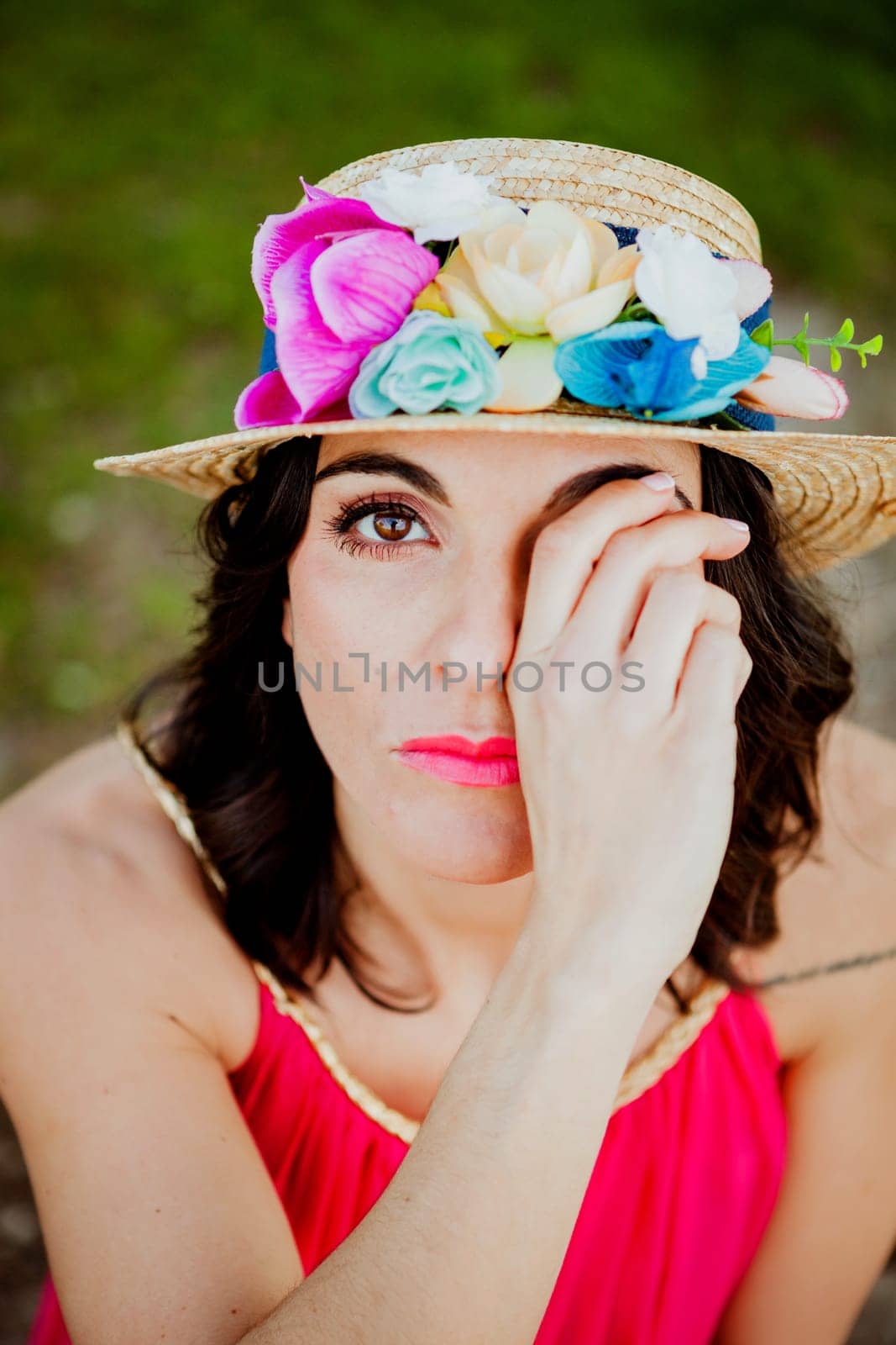 Stylish woman with a red dress and straw hat with flowers in the field