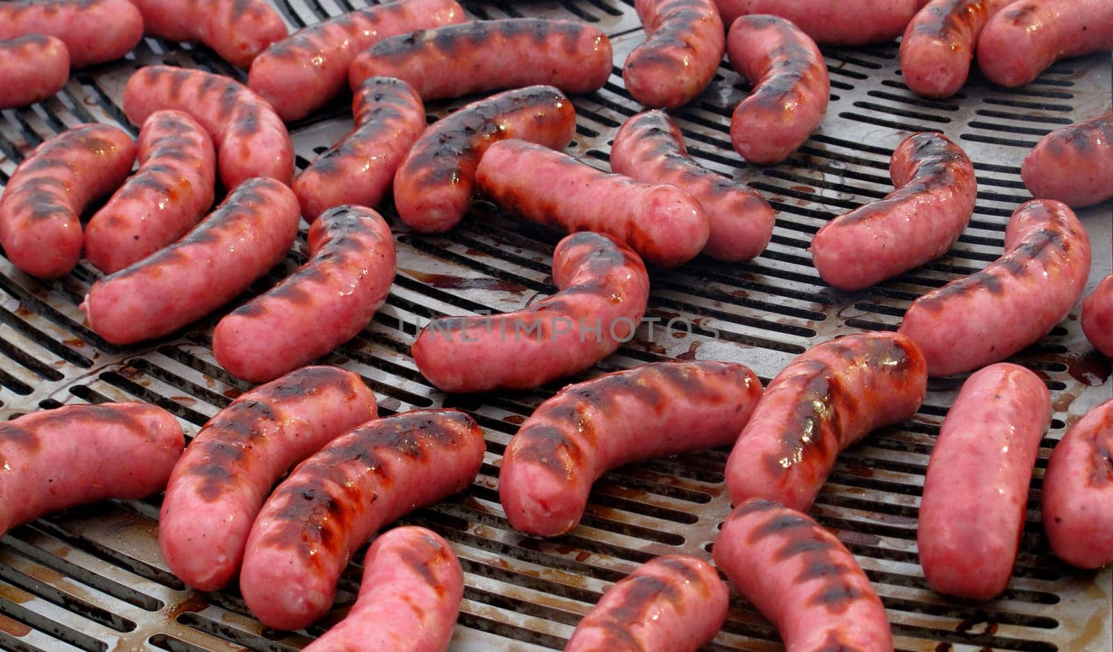 Many sausages cooking on a barbecue