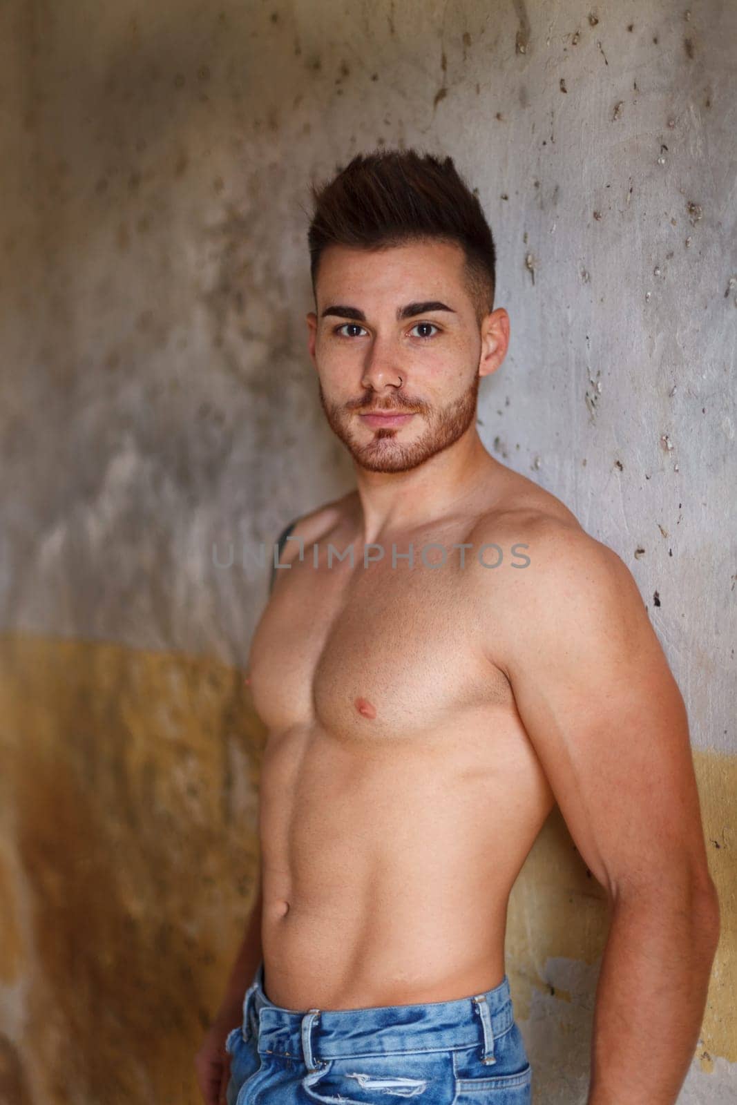 Attractive guy showing his muscles in a old house