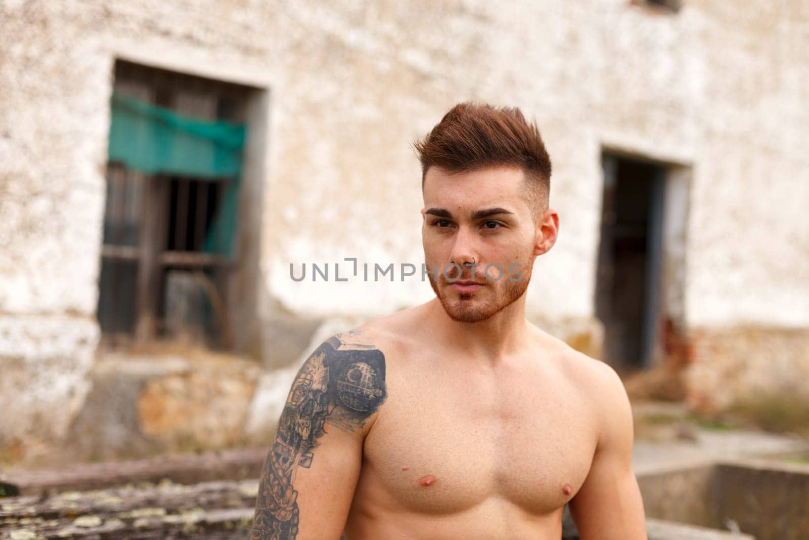 Attractive guy showing his muscles in a old house