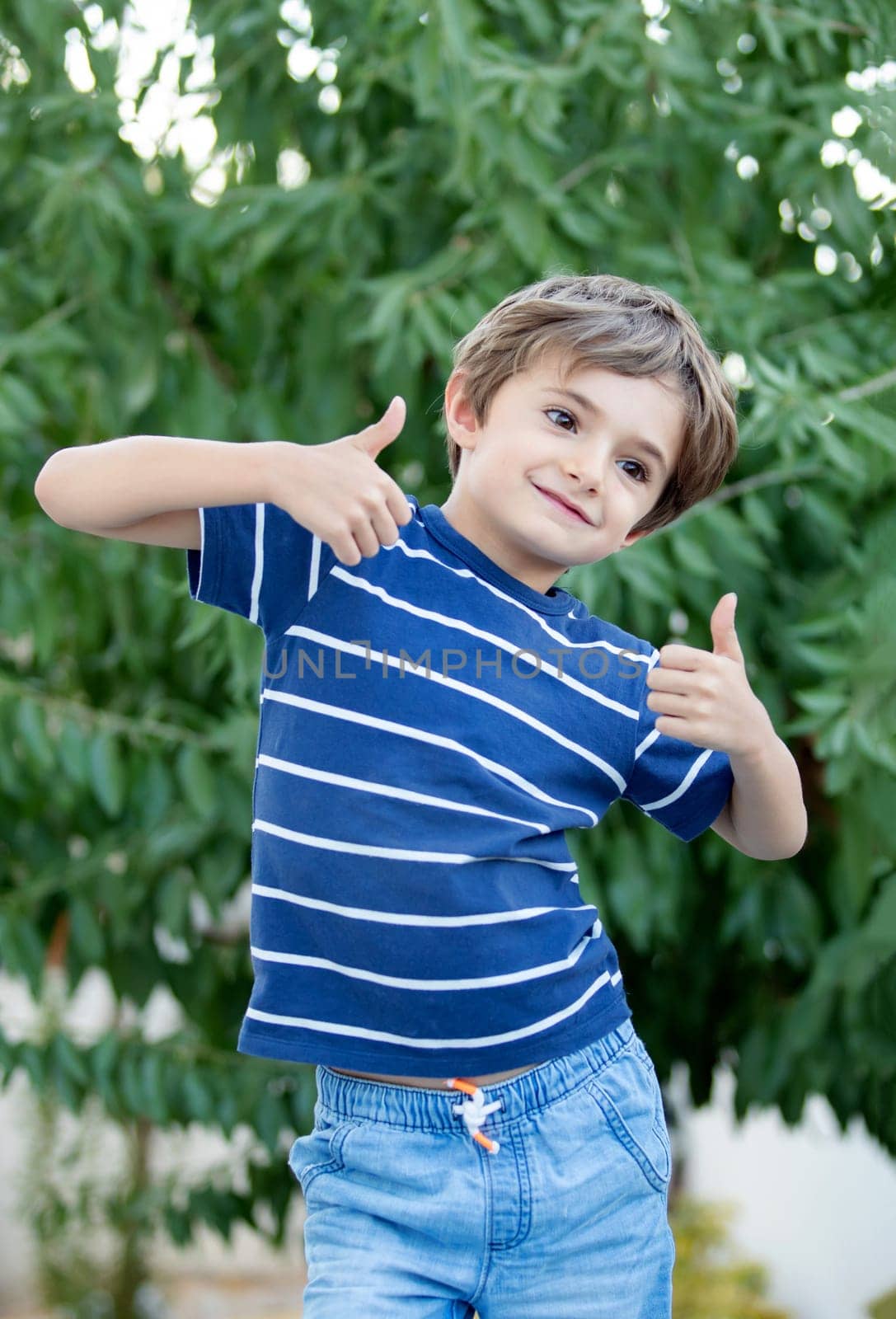 Happy child with long blond hair enjoying the nature and saying OK