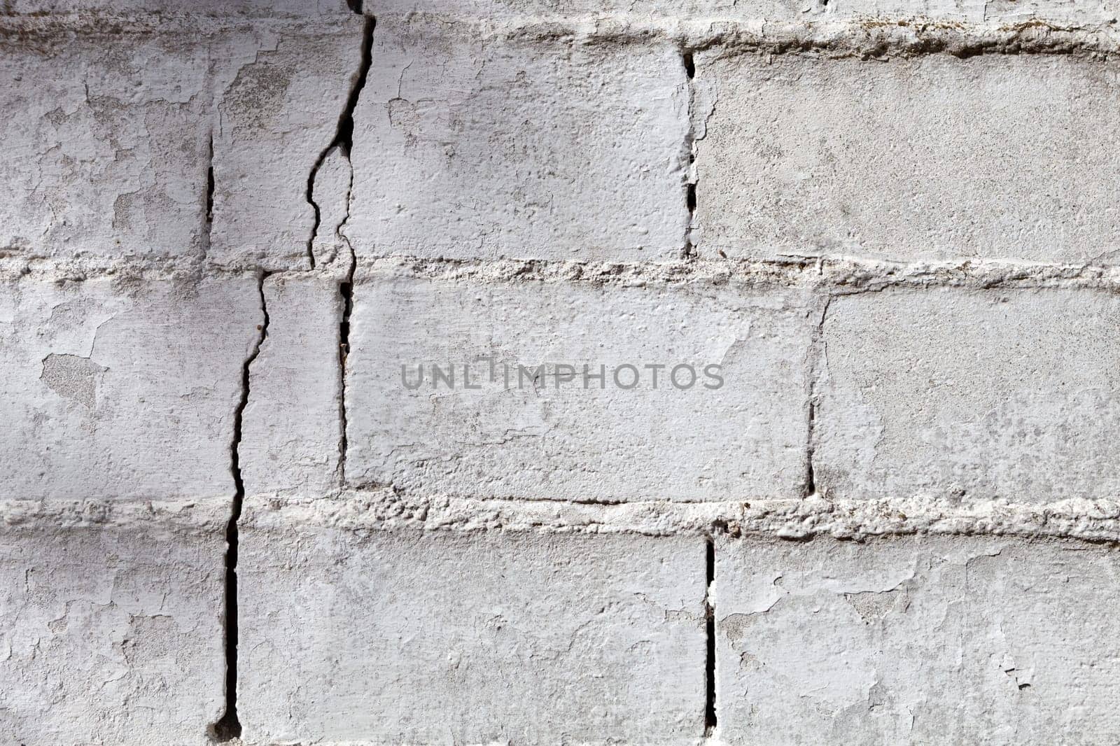 Crack in a white wall with cement brick surface
