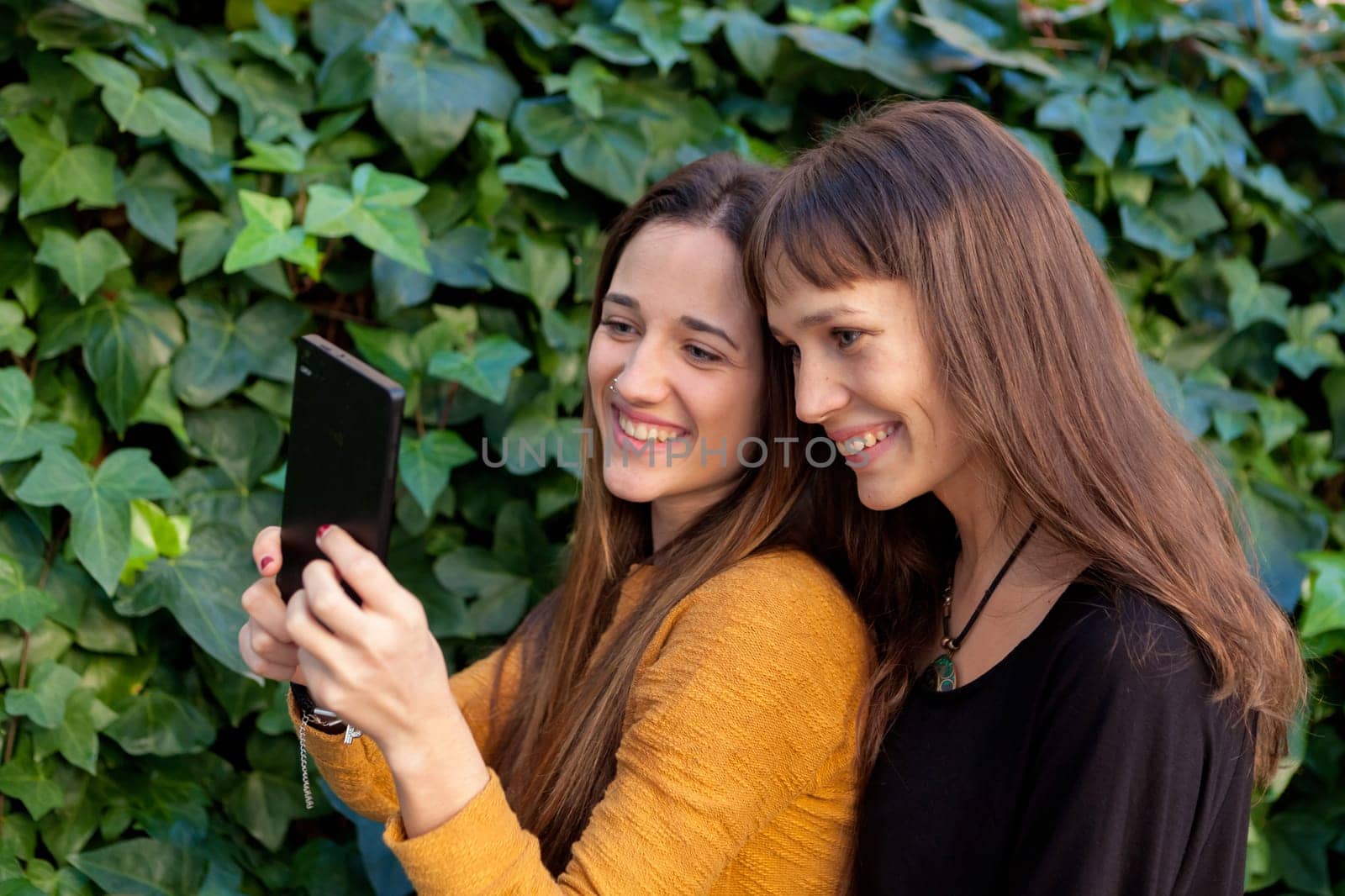 Two sisters enjoying of a day in the park with a mobile