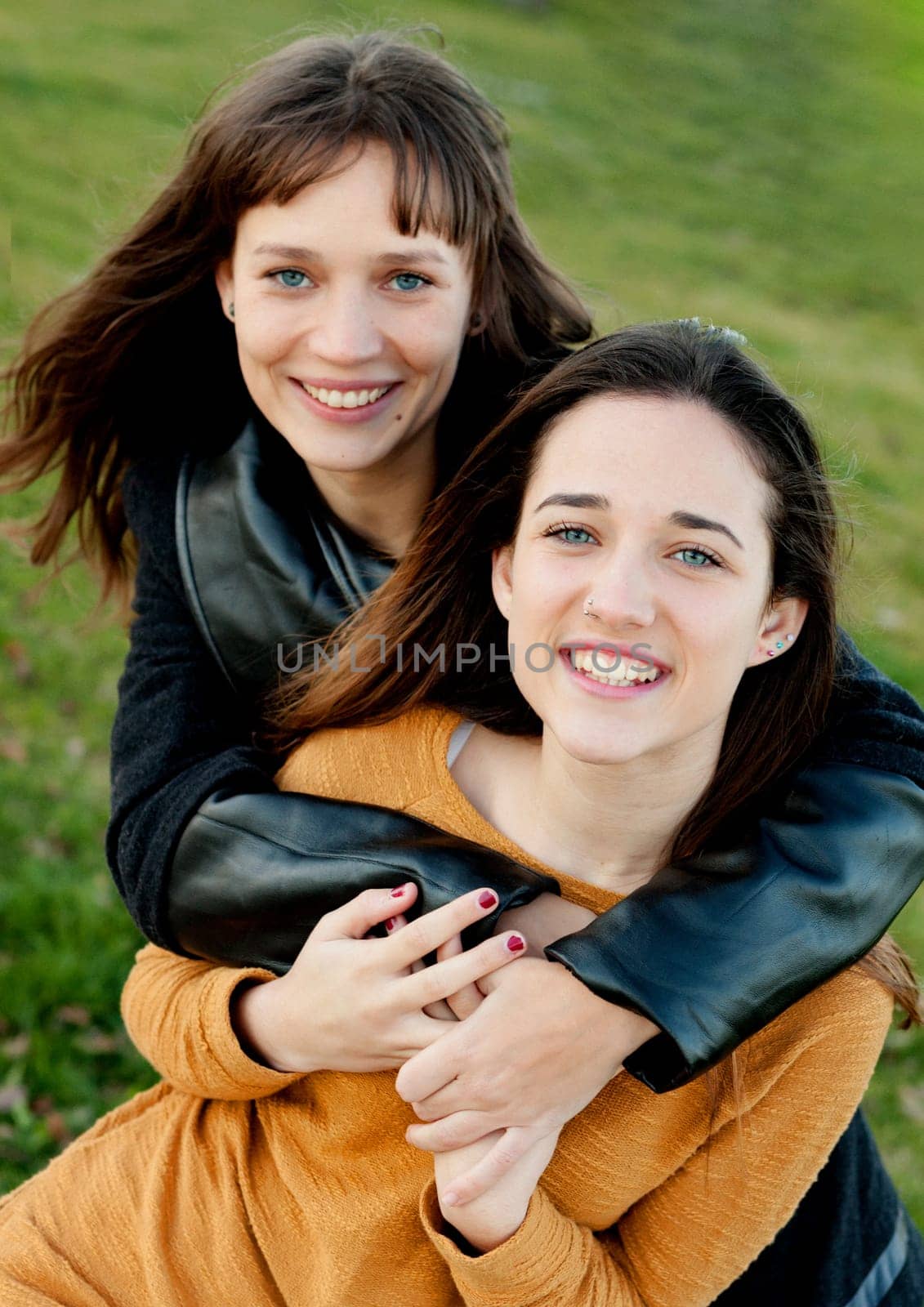 Outdoor portrait of two happy sisters relaxed in a park