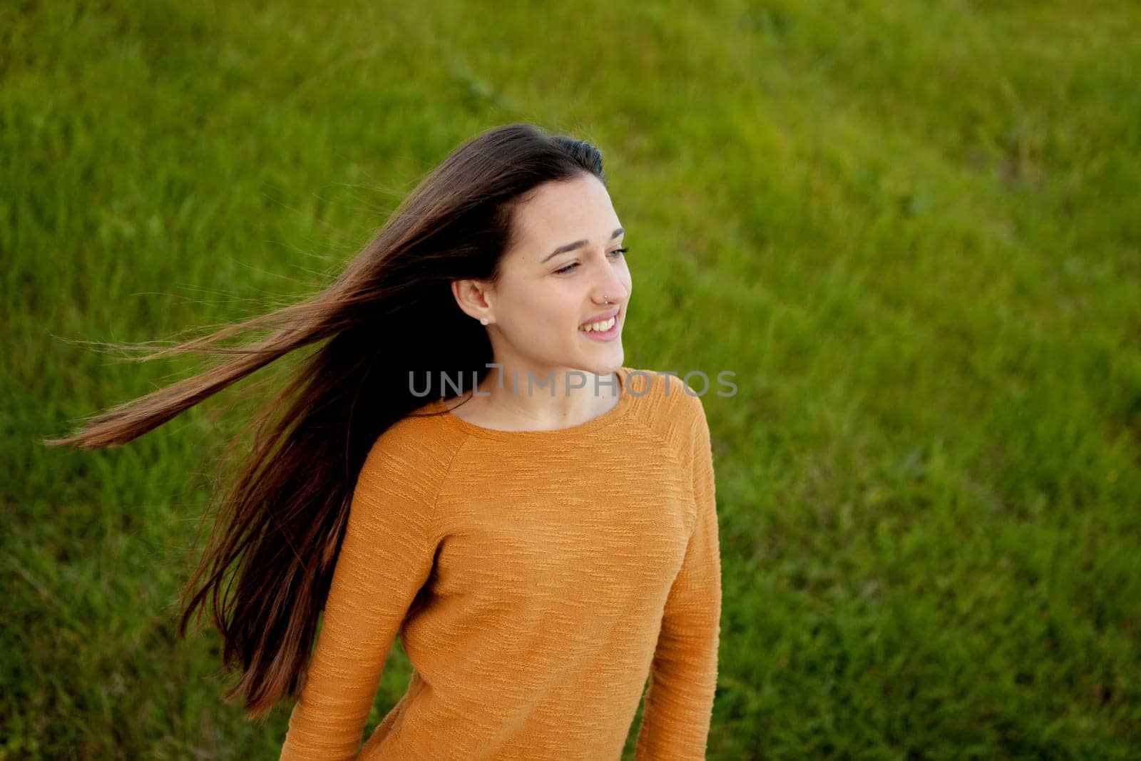 Outdoor portrait of beautiful happy teenager girl laughing with perfect teeth in field